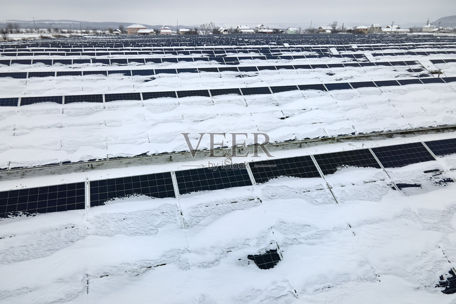 雪覆盖的可持续电力厂的鸟瞰图，排列着太阳能光伏板以生产清洁电能。北方冬季可再生电力的低效能。照片摄影图片