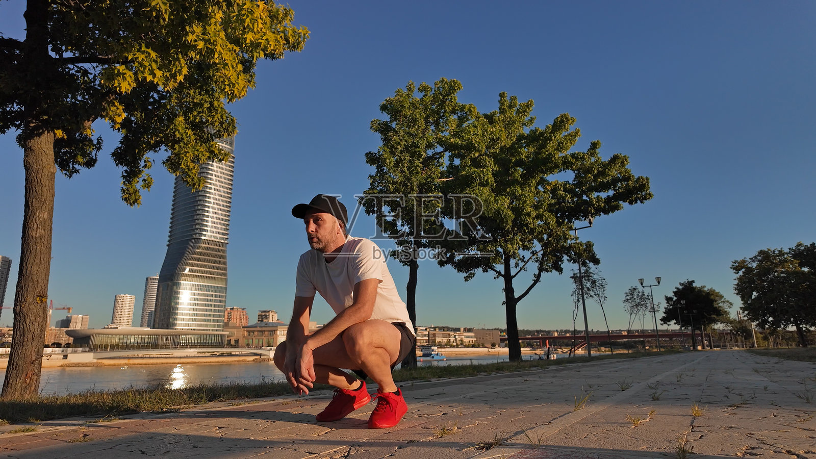 男人在日落时分的城市公园里锻炼和慢跑后休息。照片摄影图片