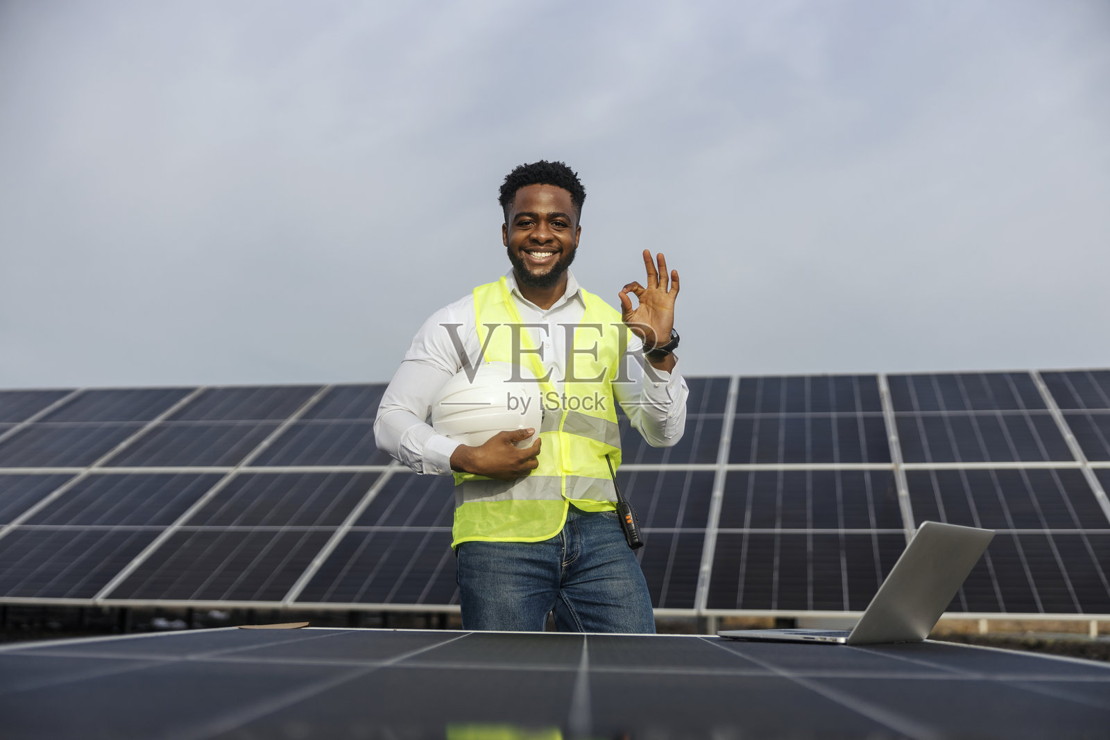 多元化的电气工程师在太阳能农场中站立，周围是太阳能电池板，向镜头做出“好的”手势。照片摄影图片