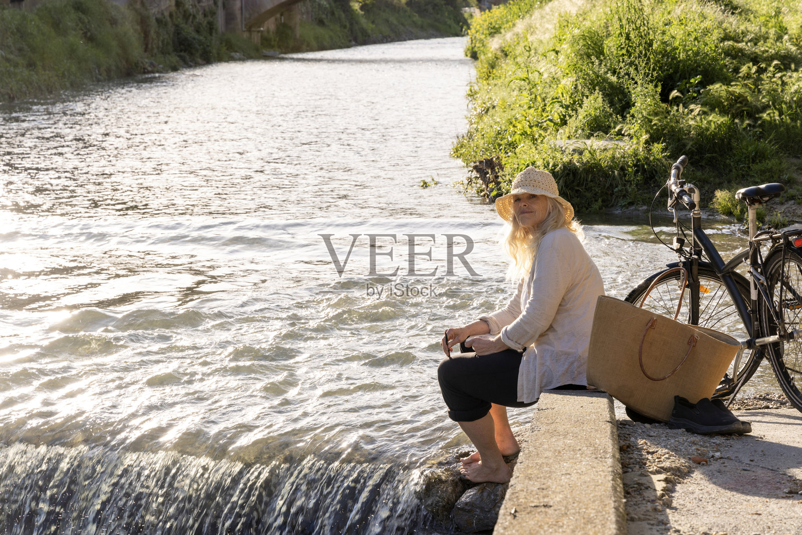 成熟的女性骑自行车在利古里亚的溪水中浸脚照片摄影图片