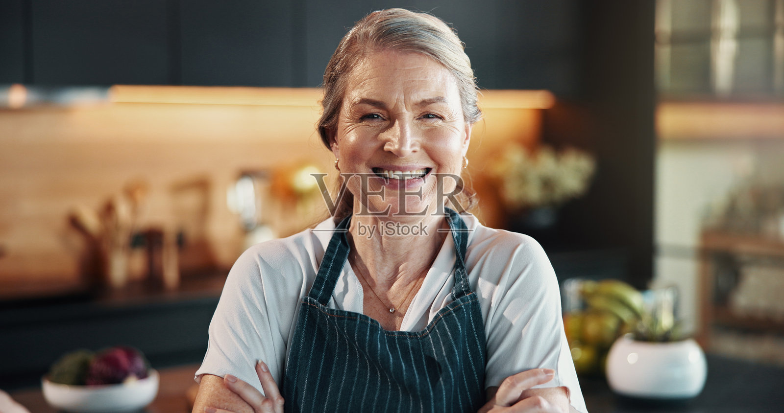 自信的女性厨师在家中骄傲地展示烹饪技巧和热情好客的服务。微笑、成熟的人双臂交叉，展现出烹饪的雄心、餐饮行业和个性化菜单。照片摄影图片
