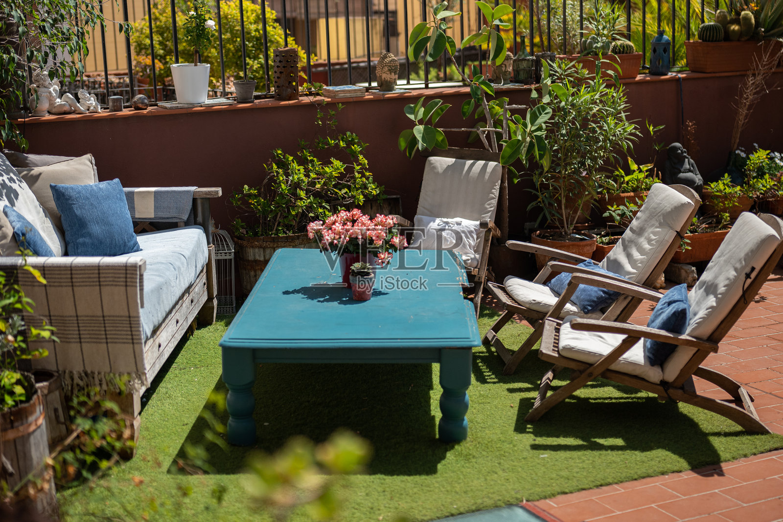 舒适的户外休息区，配有木质家具、郁郁葱葱的植物和一张蓝色乡村风格的咖啡桌照片摄影图片