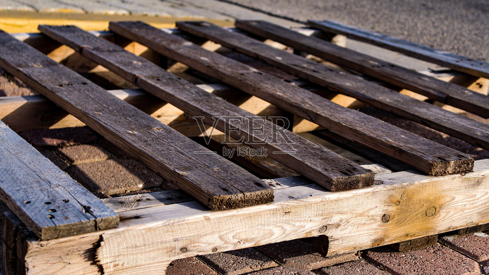 木托盘特写，背景是砖瓦地面和沥青。照片摄影图片