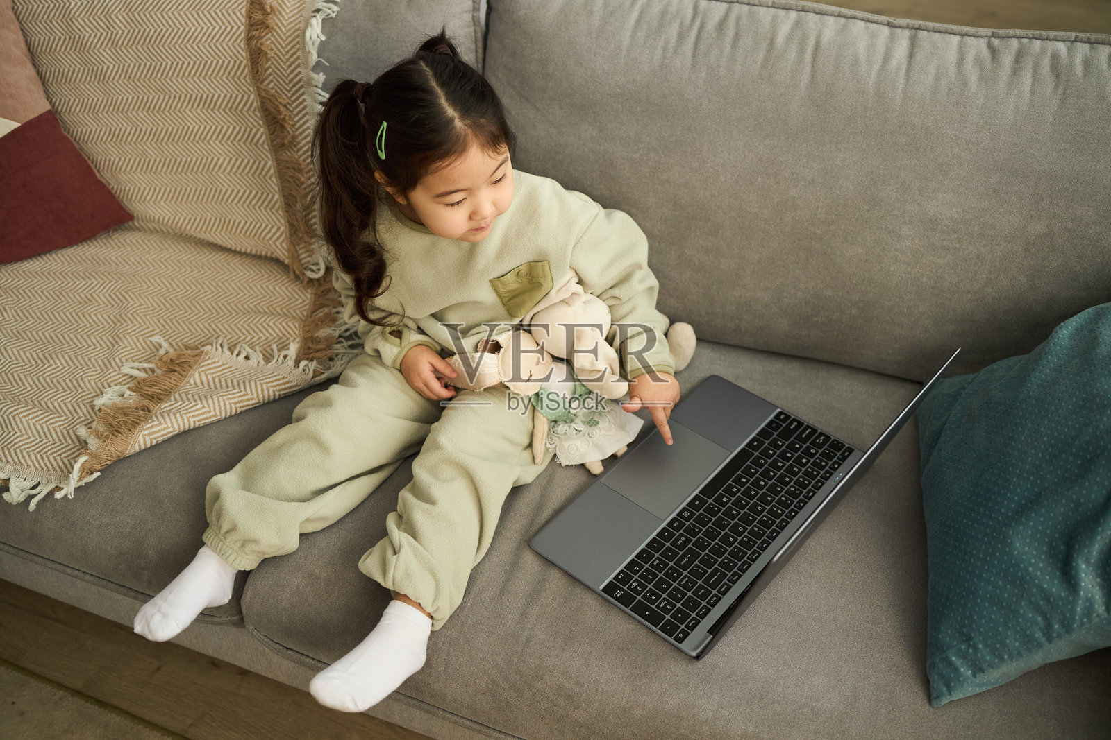 小女孩坐在沙发上抱着毛绒玩具照片摄影图片