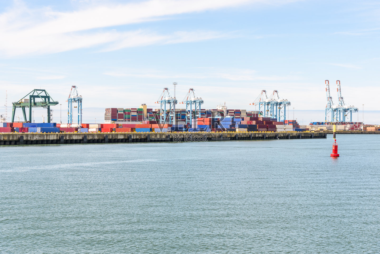 商业港口，矗立着高大的龙门吊，五彩缤纷的集装箱在部分多云的夏日中。照片摄影图片