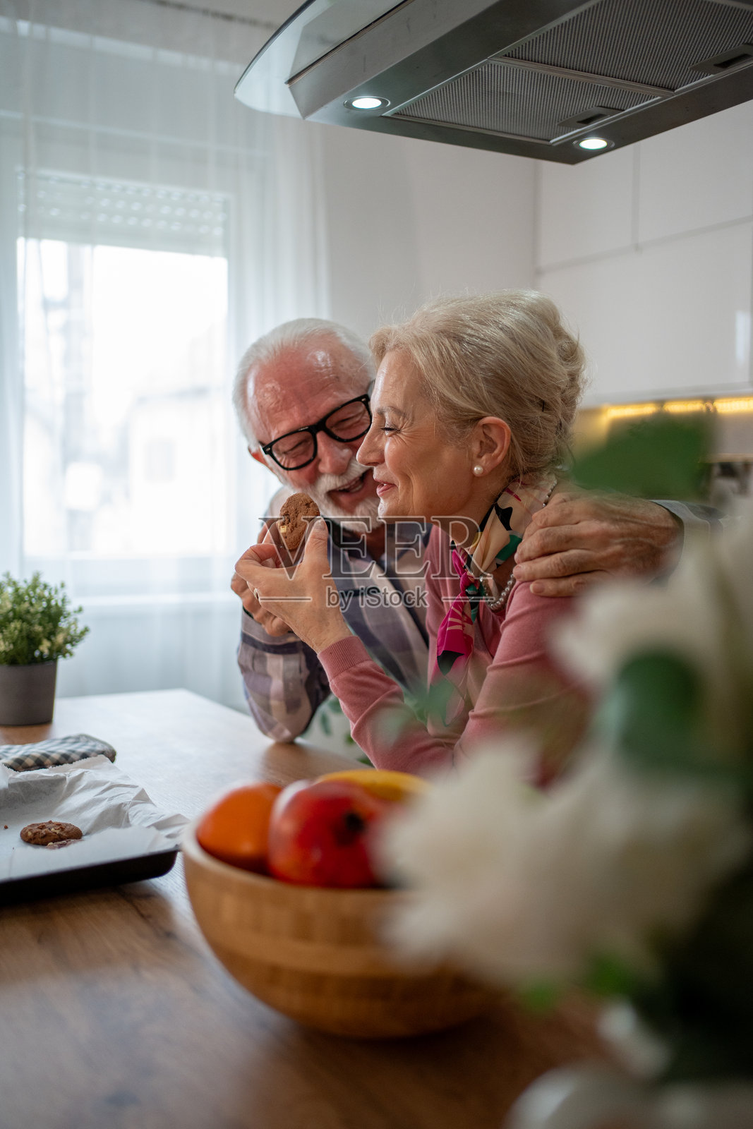 快乐的老年夫妇在现代厨房里分享一块饼干照片摄影图片