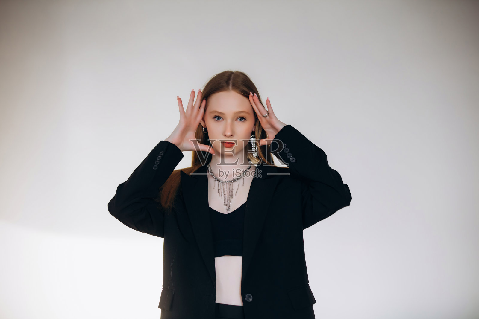 美丽的金发模特，年轻女孩，青少年，穿着黑色夹克在白色背景幕布的摄影棚里照片摄影图片