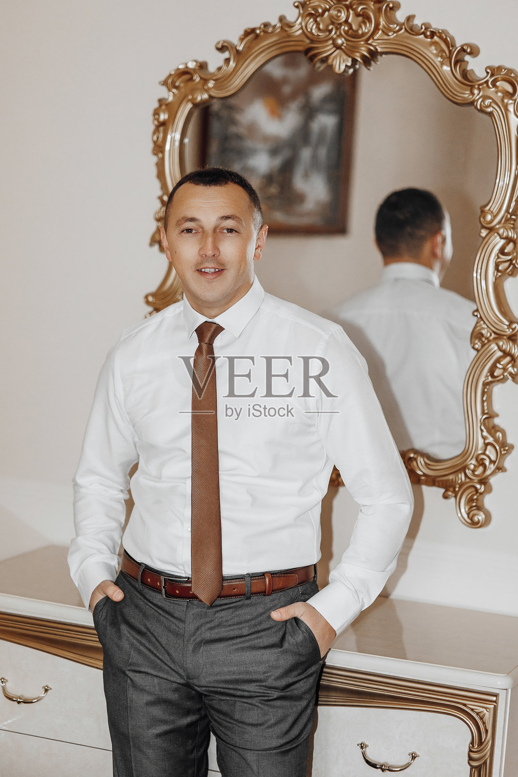 一名穿着西装和领带的男子站在镜子前。照片摄影图片