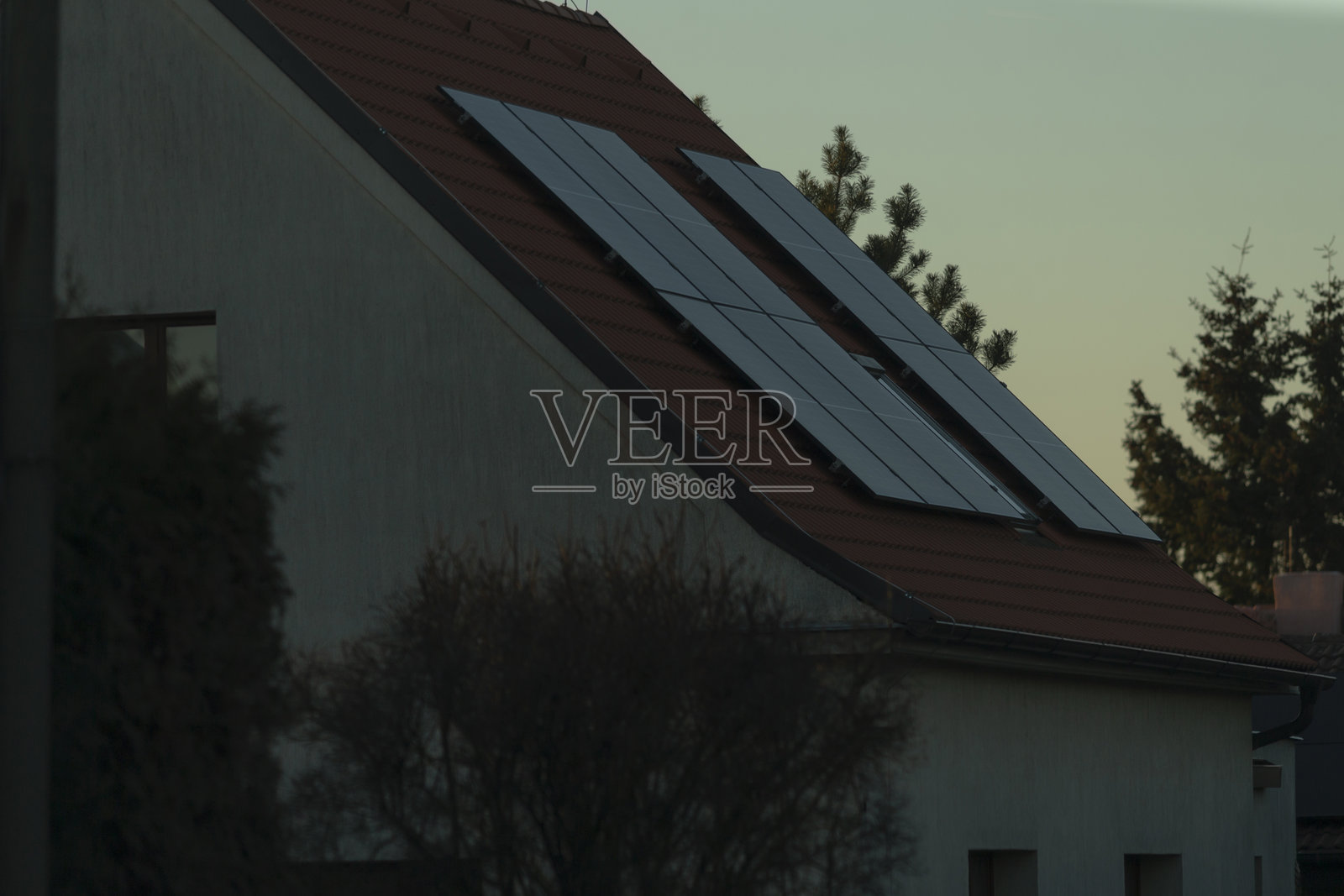 黄昏时分，屋顶太阳能电池板被美丽的灯光照亮照片摄影图片