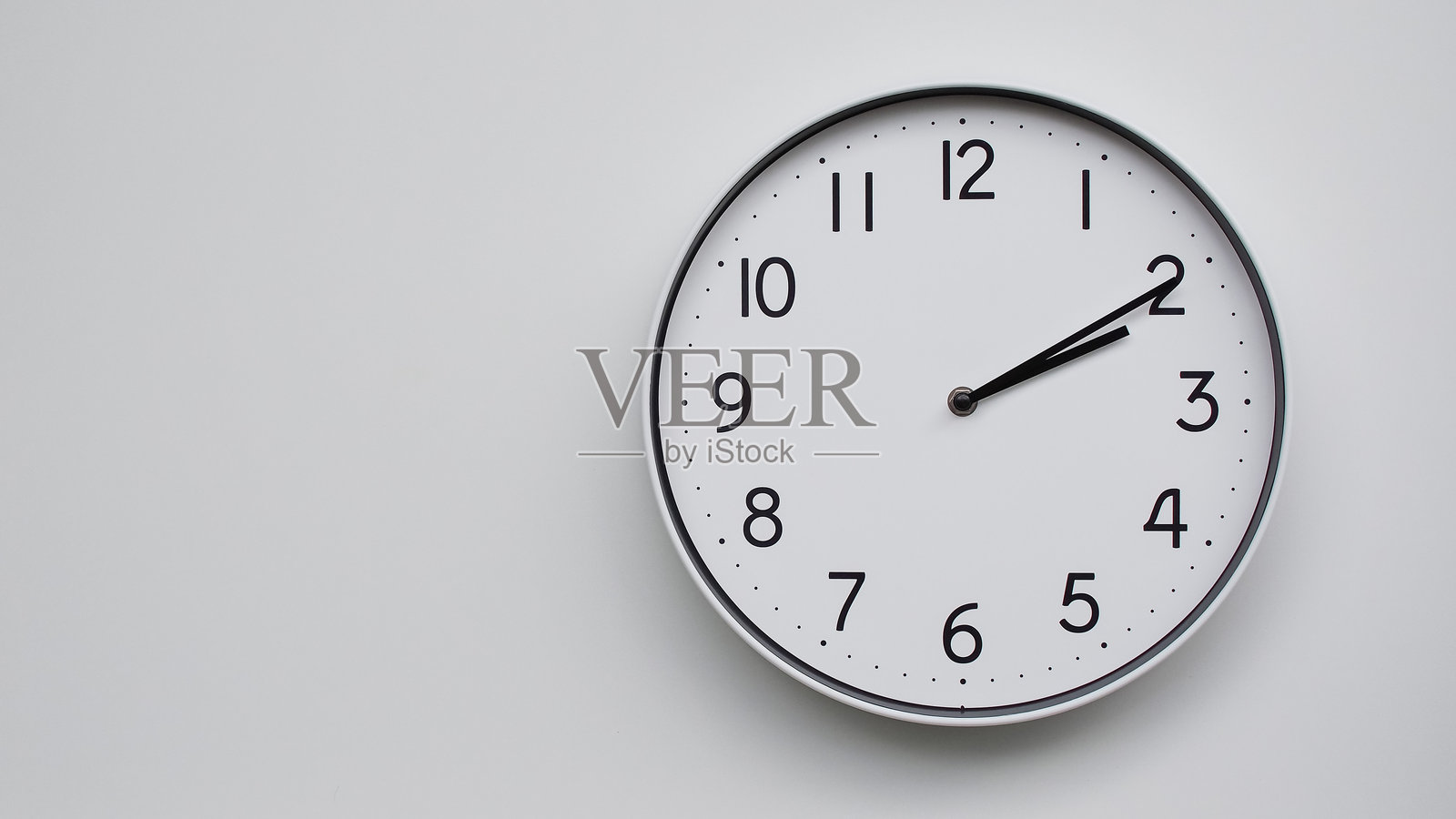 极简主义白色表盘的模拟挂钟，简单的黑色指针显示14:10/02:10 - 适合时间管理和现代装饰理念照片摄影图片