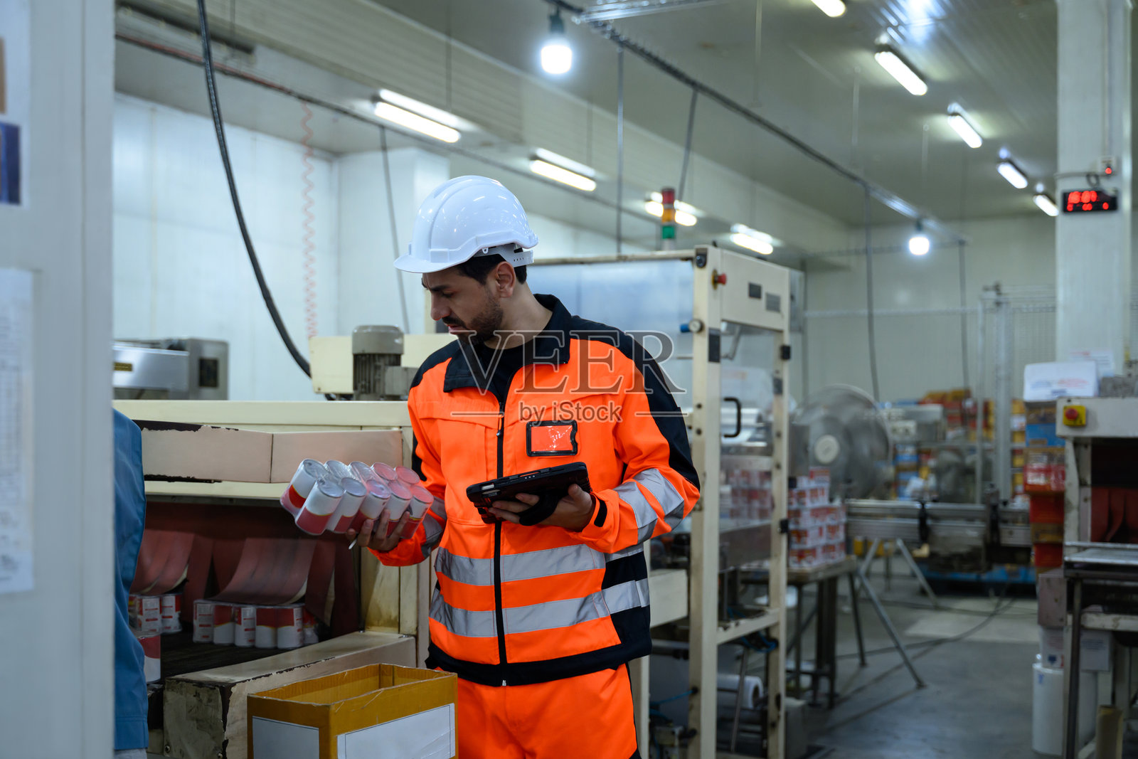 检查员手持数字平板电脑，在食品加工厂检查产品质量照片摄影图片