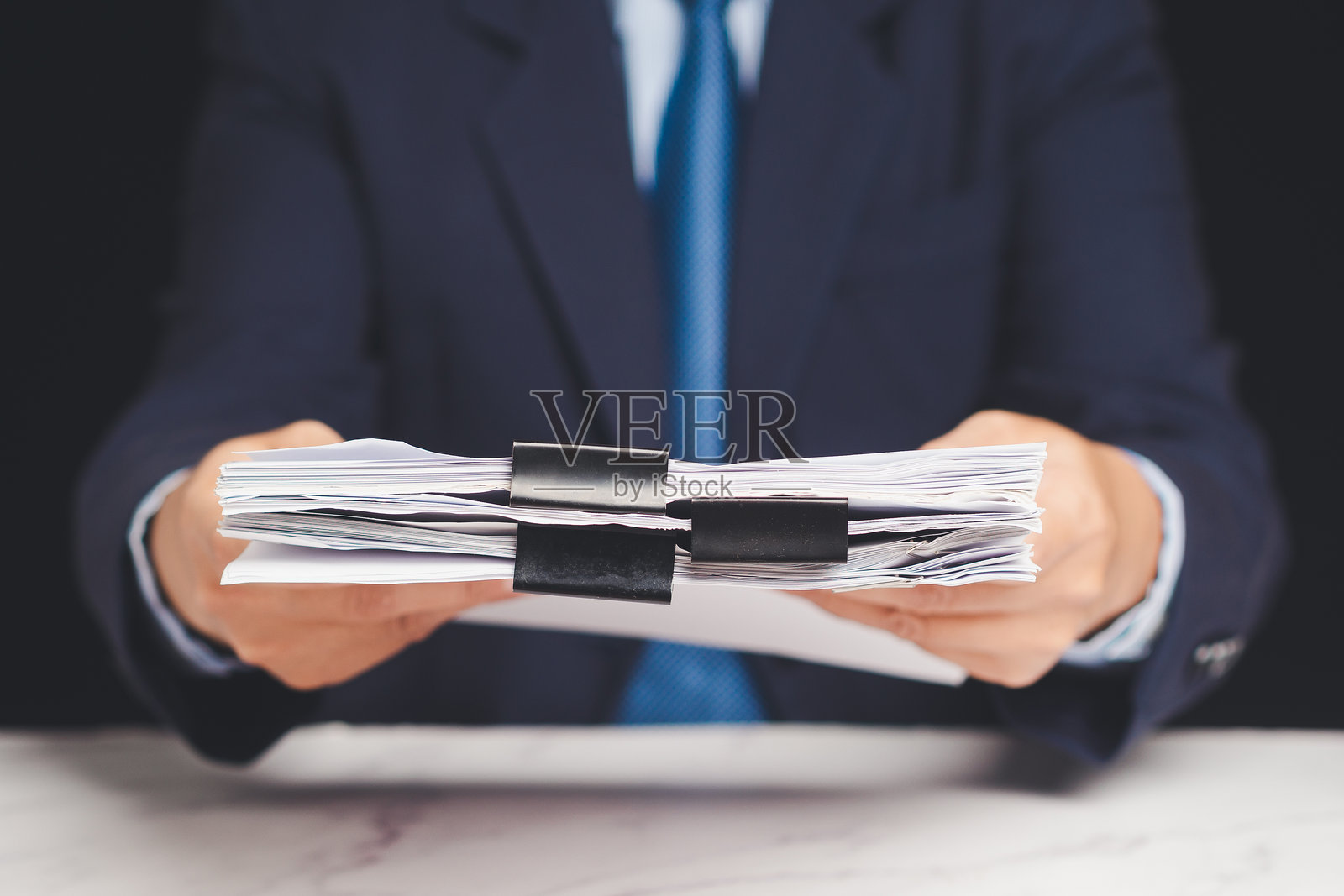 商人递交一叠纸质文件以供审批或审核的特写镜头。照片摄影图片