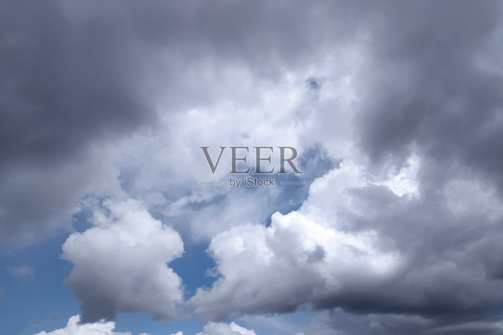 戏剧性的云景，黑暗的暴风云与蓝天的闪现形成对比。唤起在逆境中希望的感觉，变化或过渡。非常适合天气报告或背景使用。照片摄影图片