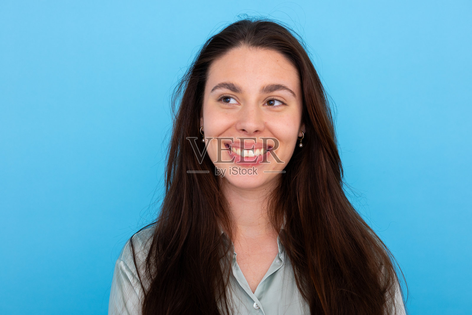 面带灿烂笑容的快乐女性转头，背景为明亮的蓝色。照片摄影图片