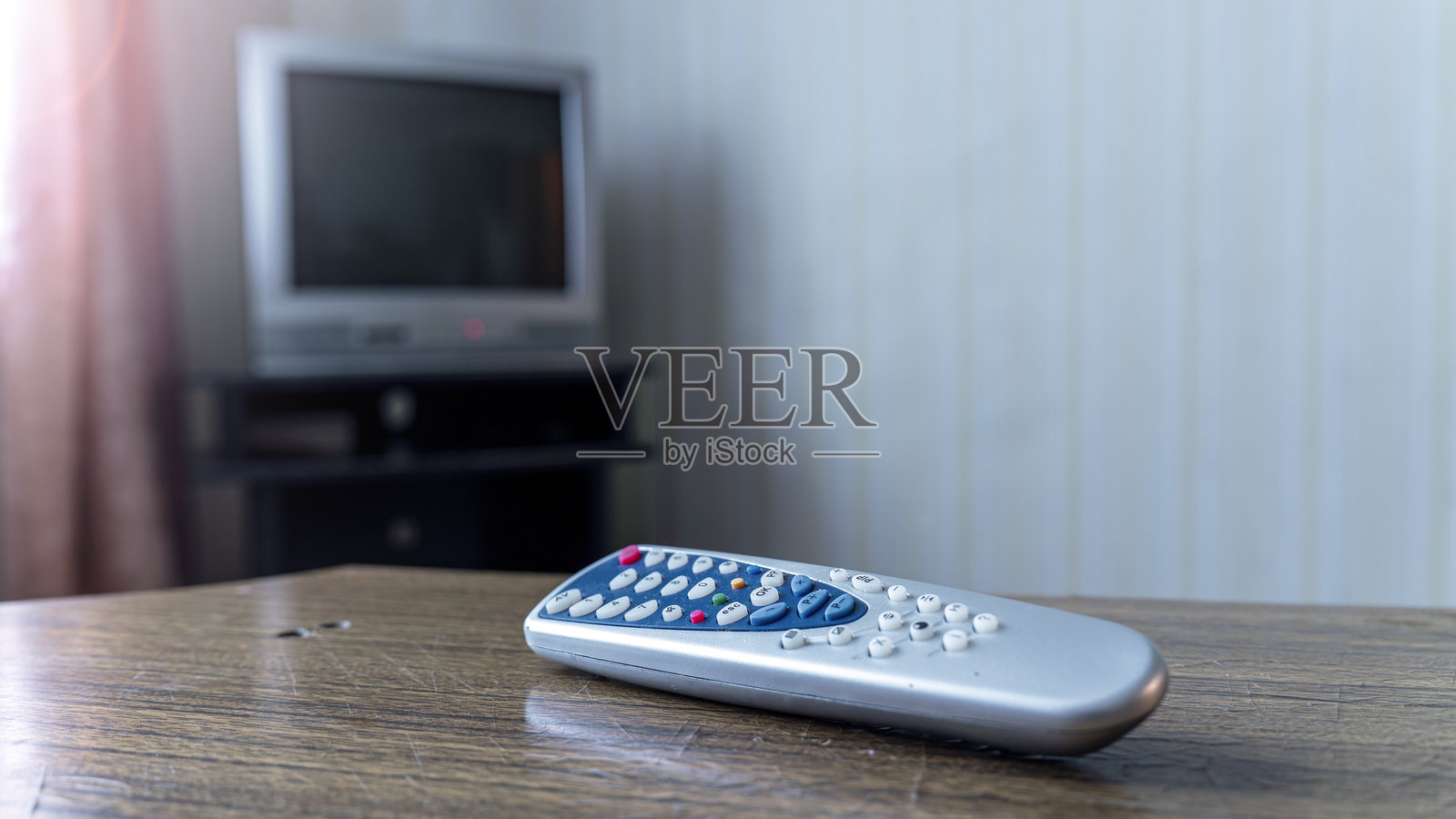 电视遥控器放在电视屏幕旁，展现家庭的放松与娱乐。照片摄影图片