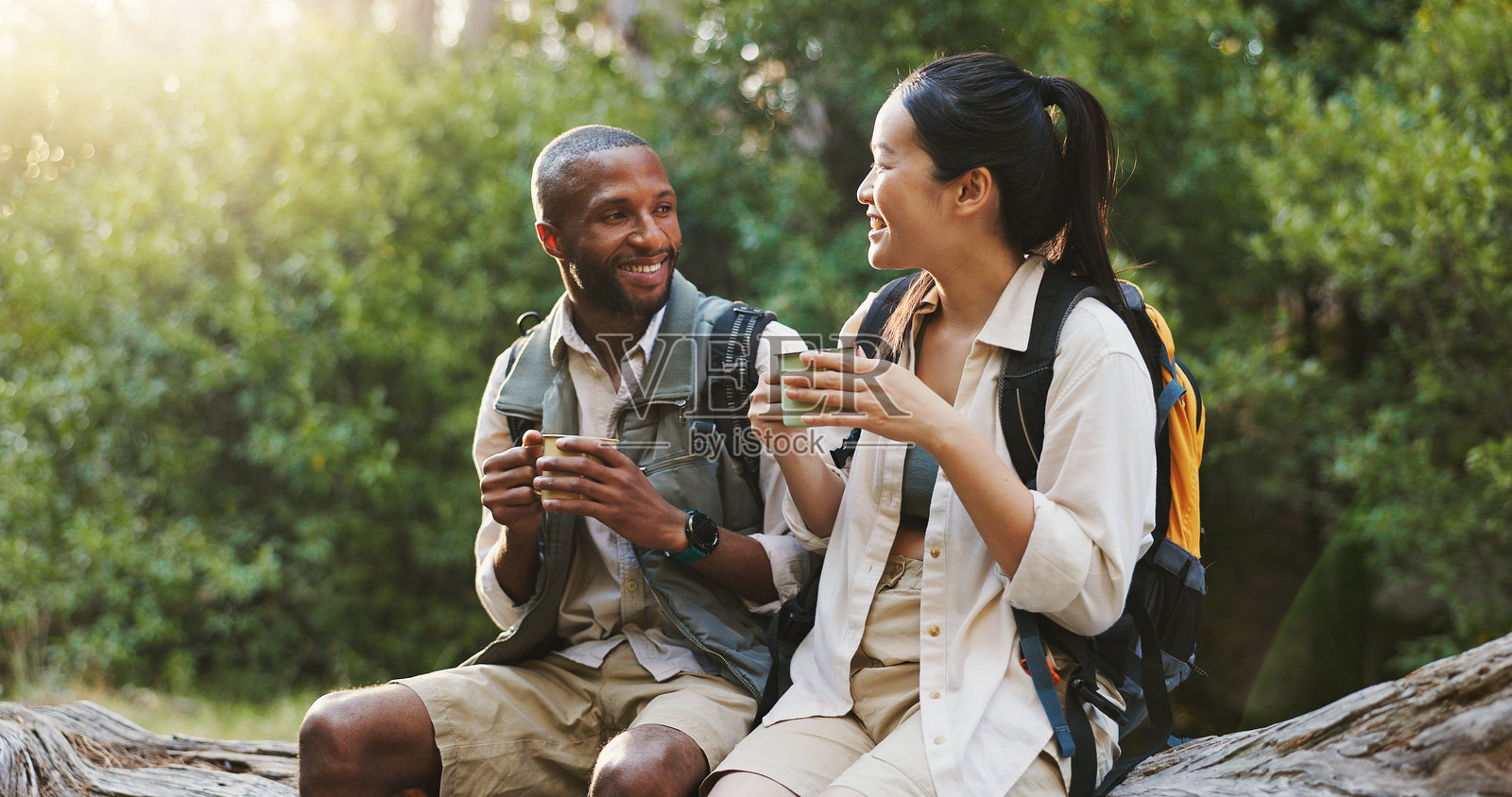 微笑、咖啡和在大自然中与跨种族情侣的徒步旅行午餐休息，探险和公园旅行。喝茶、交谈和森林环境中的男女。照片摄影图片