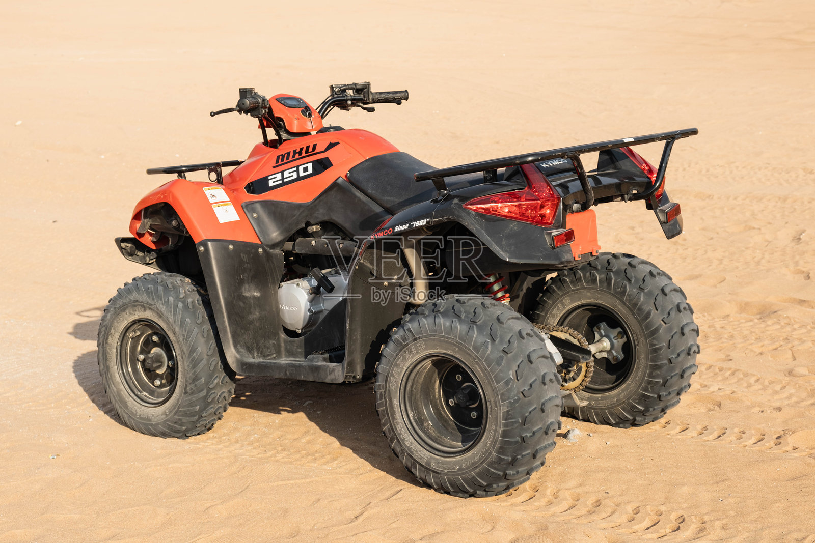 阳光明媚下的沙地上红色全地形车照片摄影图片