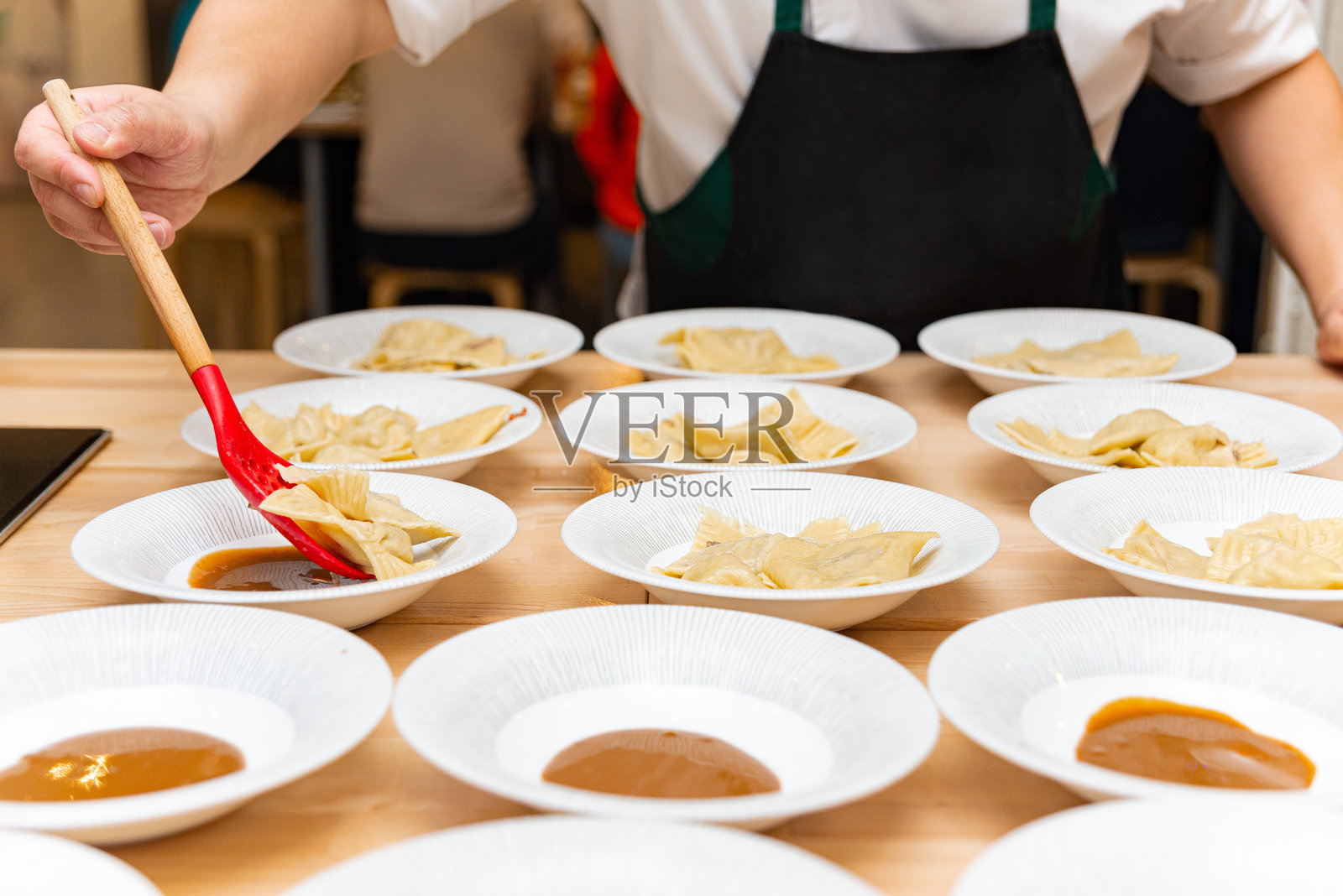 厨师在餐厅为意大利饺子装盘并淋上酱汁。照片摄影图片