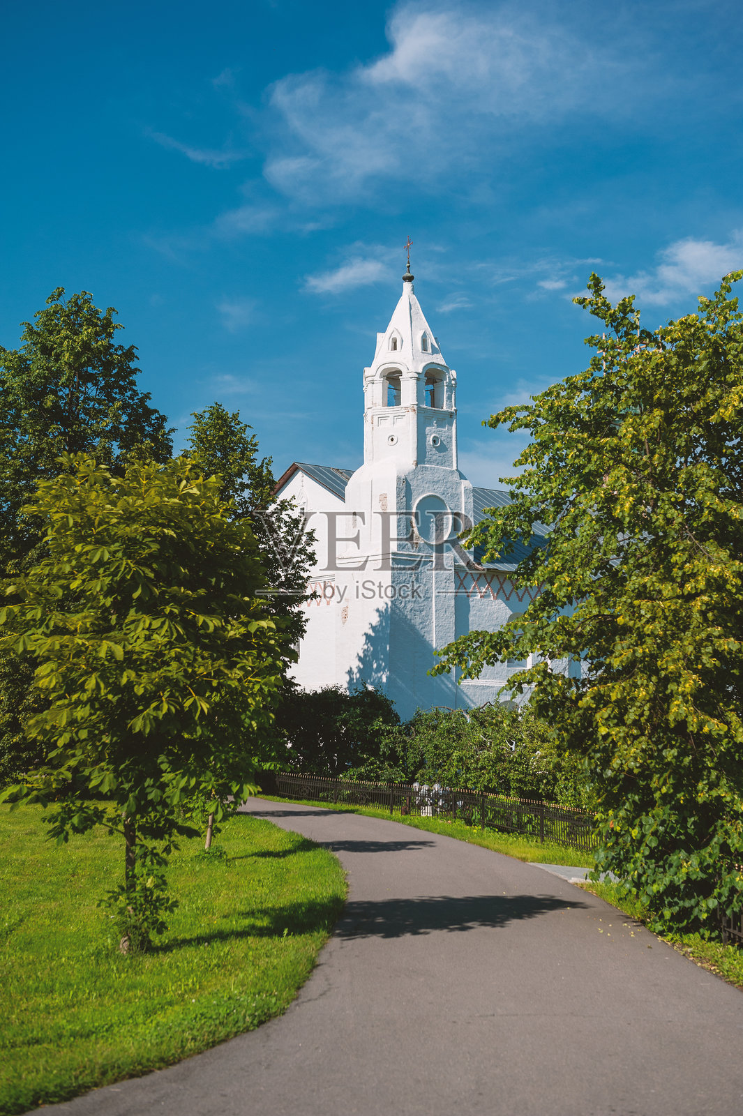 白色东正教教堂与高耸的钟楼在蓝色夏日天空下。照片摄影图片