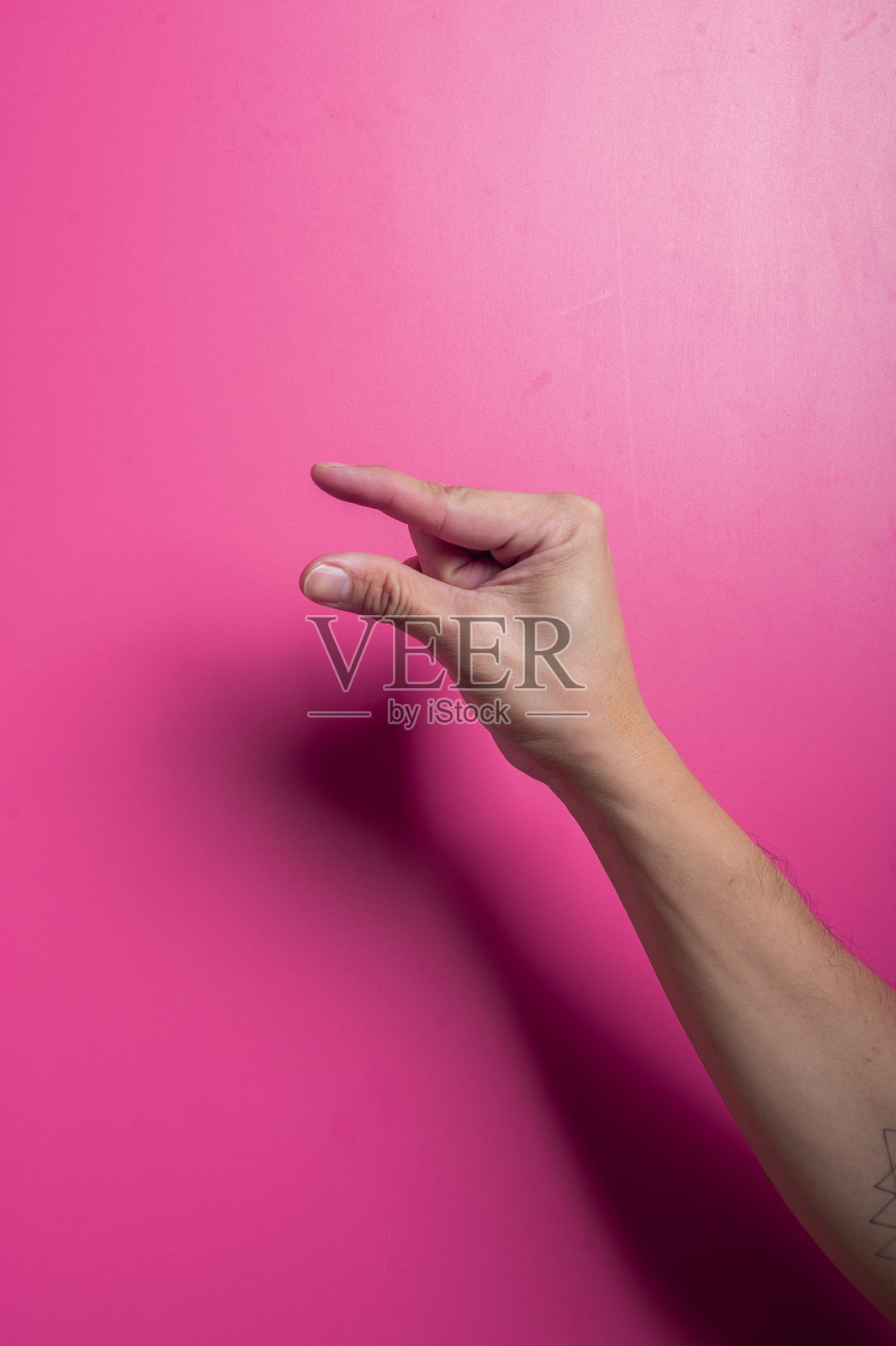 亚洲手指在粉色背景下紧紧捏在一起，象征着小尺寸、少量或微小细节，展现出清晰而富有表现力的现代手势。照片摄影图片