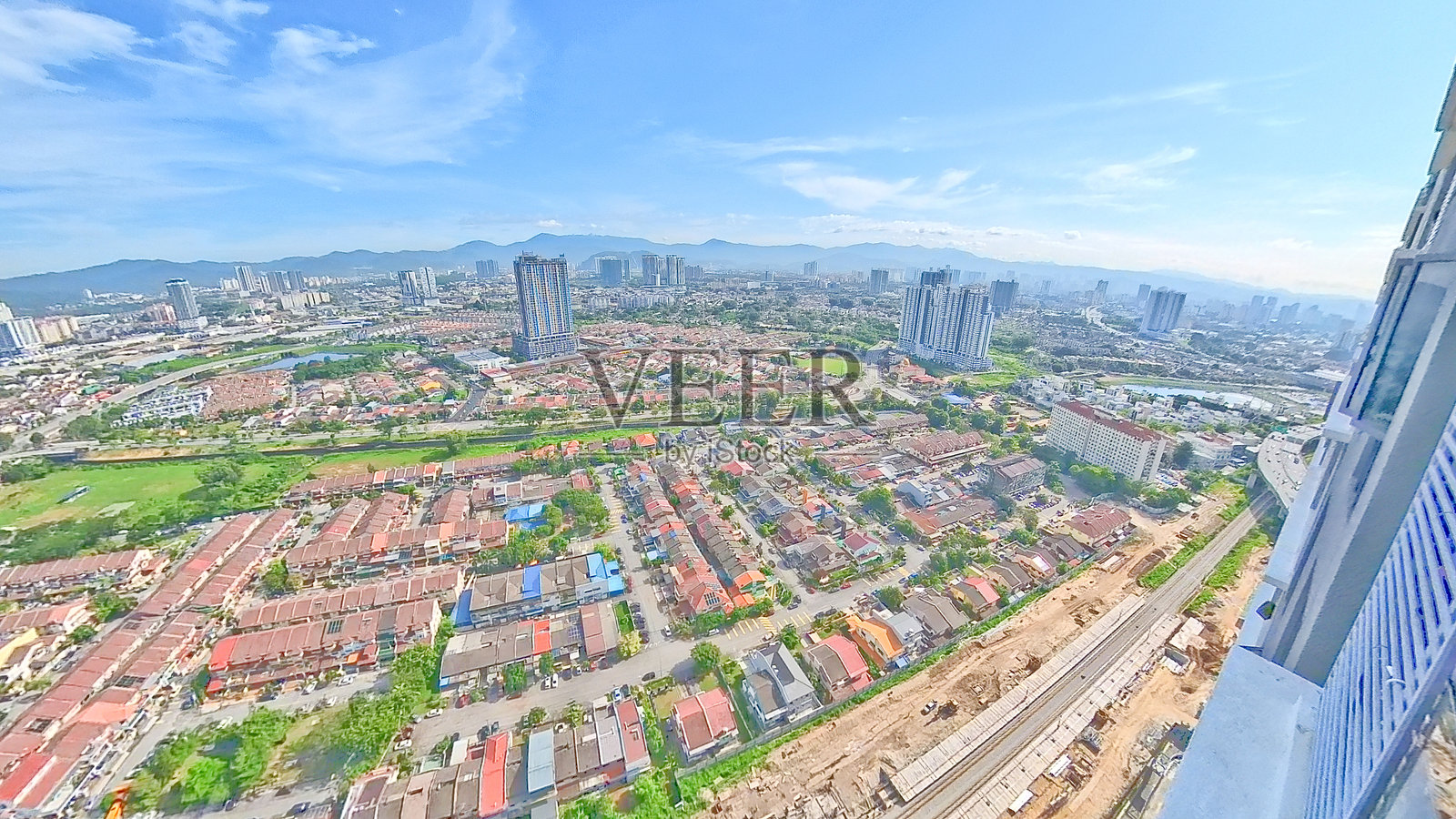 马来西亚，吉隆坡。城市的明亮鸟瞰图，展示了住宅房屋、高层建筑、铁路轨道和背景中的山脉。照片摄影图片