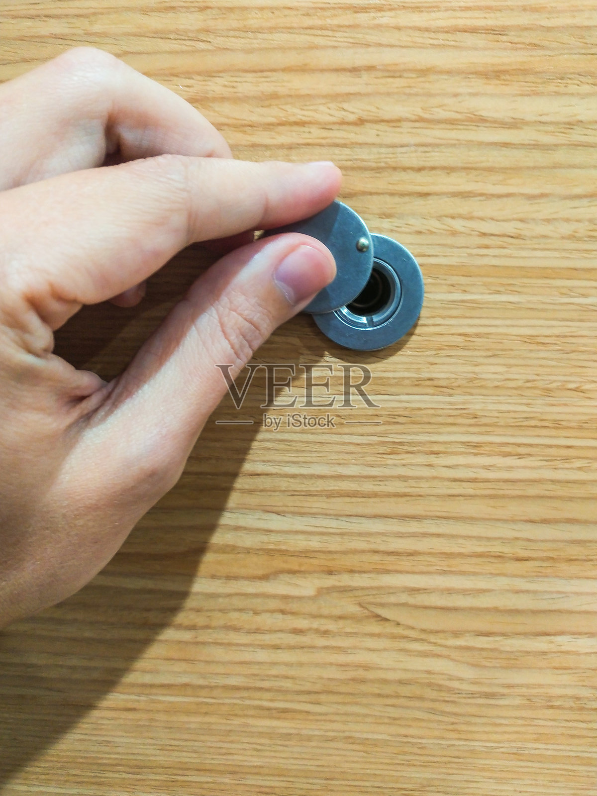 手打开木门上的窥视孔盖，特写。代表隐私、安全和期待。可用于家庭安全、访问控制和财产主题。照片摄影图片