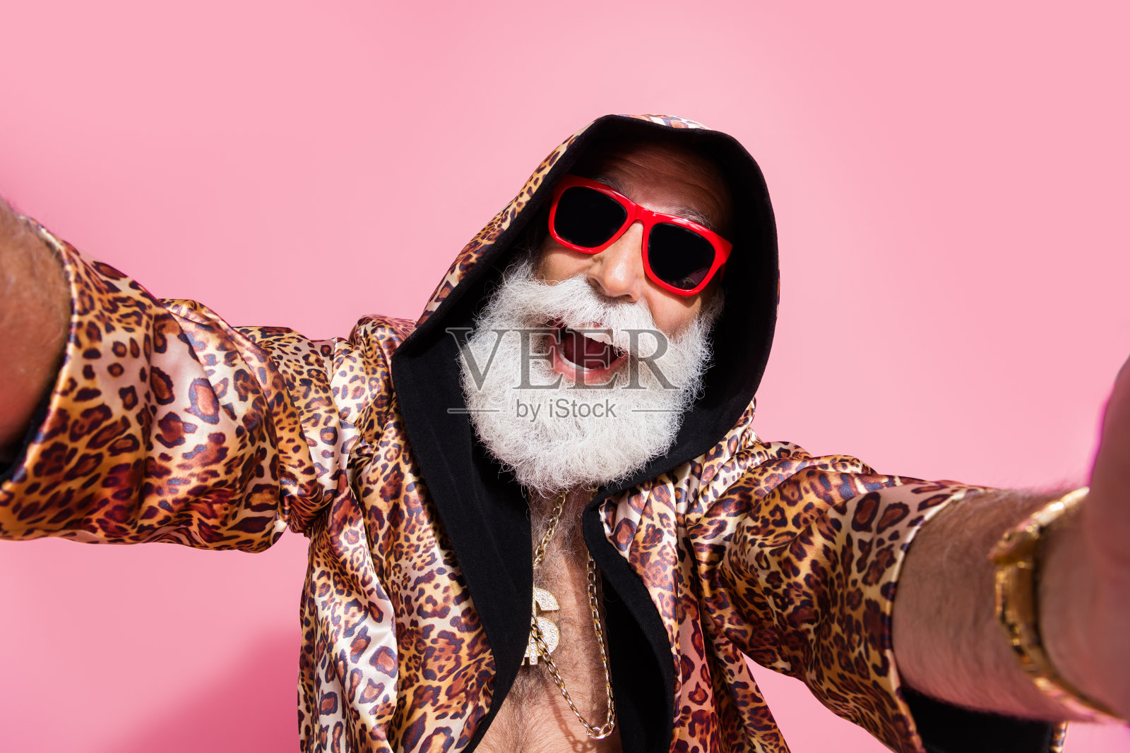 穿着时尚豹纹服装的迷人爷爷在粉色背景下自拍照片摄影图片
