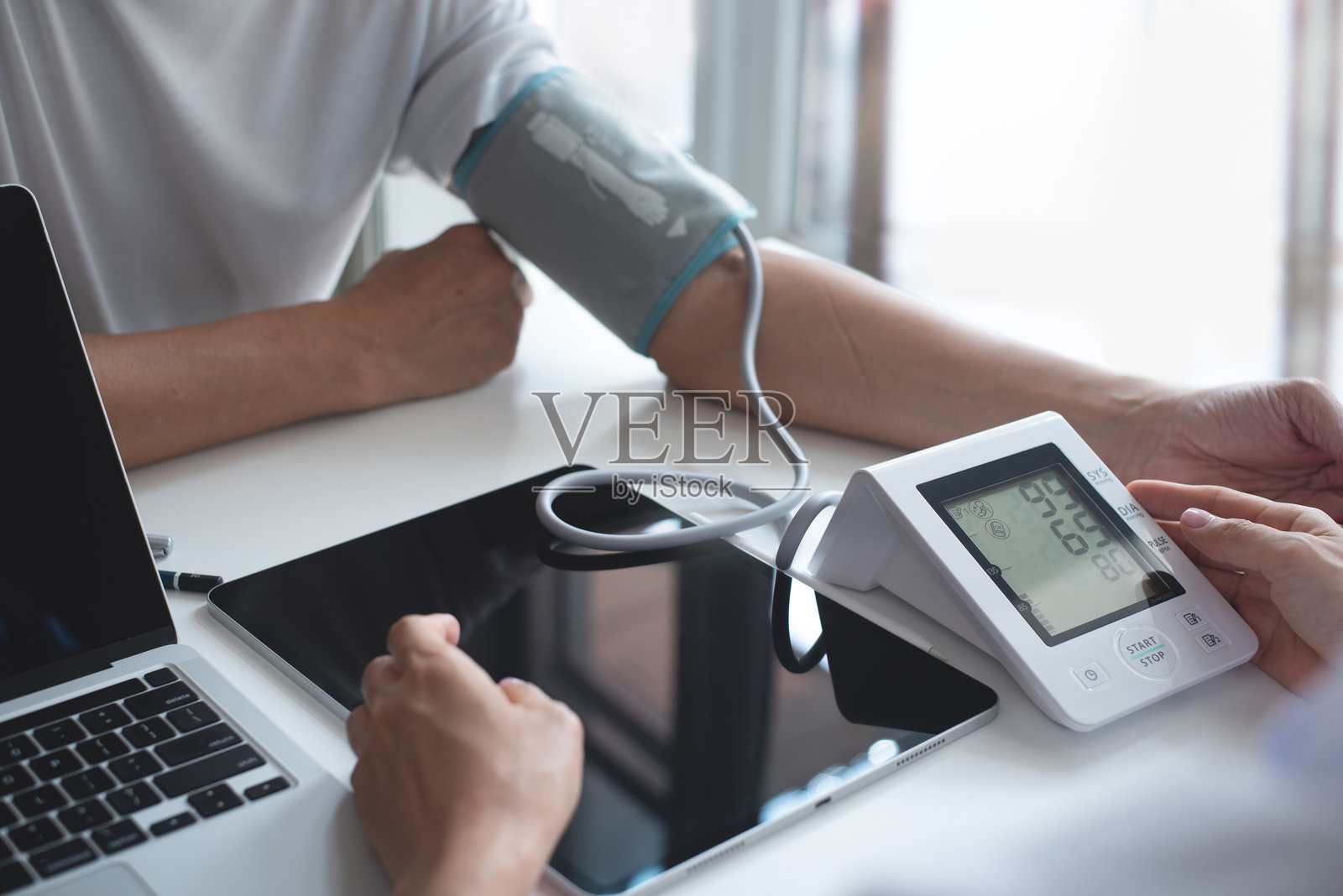 医生在医院或医疗诊所为男性患者检查心率并使用血压监测仪测量血压。照片摄影图片