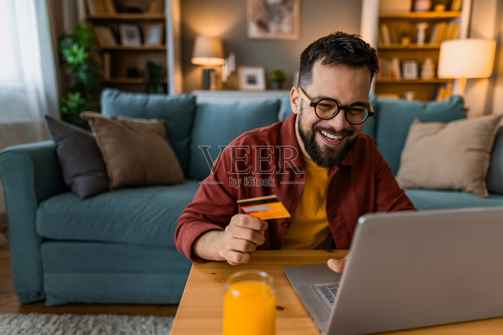 快乐的男人在家里用信用卡网上购物。照片摄影图片