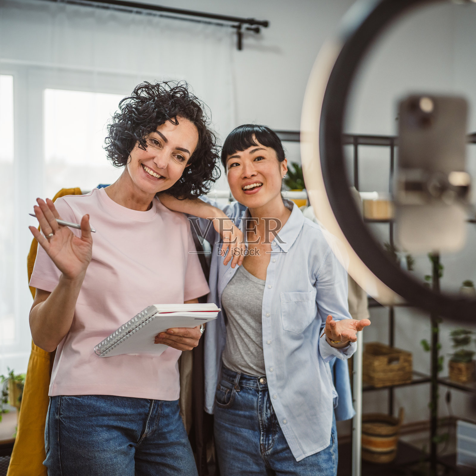 两位多元化女性在家中通过手机直播售卖衣服照片摄影图片