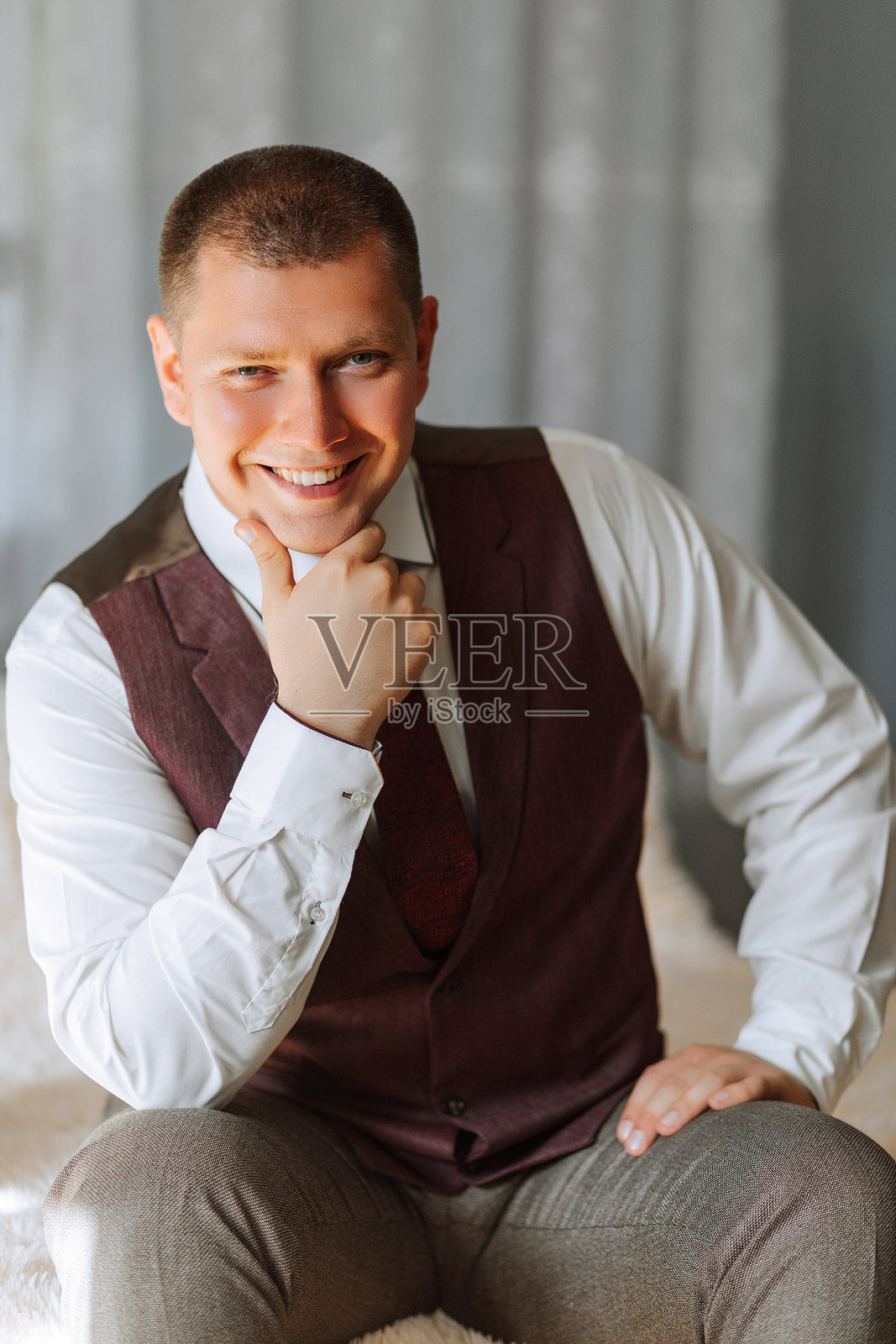 一名穿着西装和背心的男子坐在床上照片摄影图片