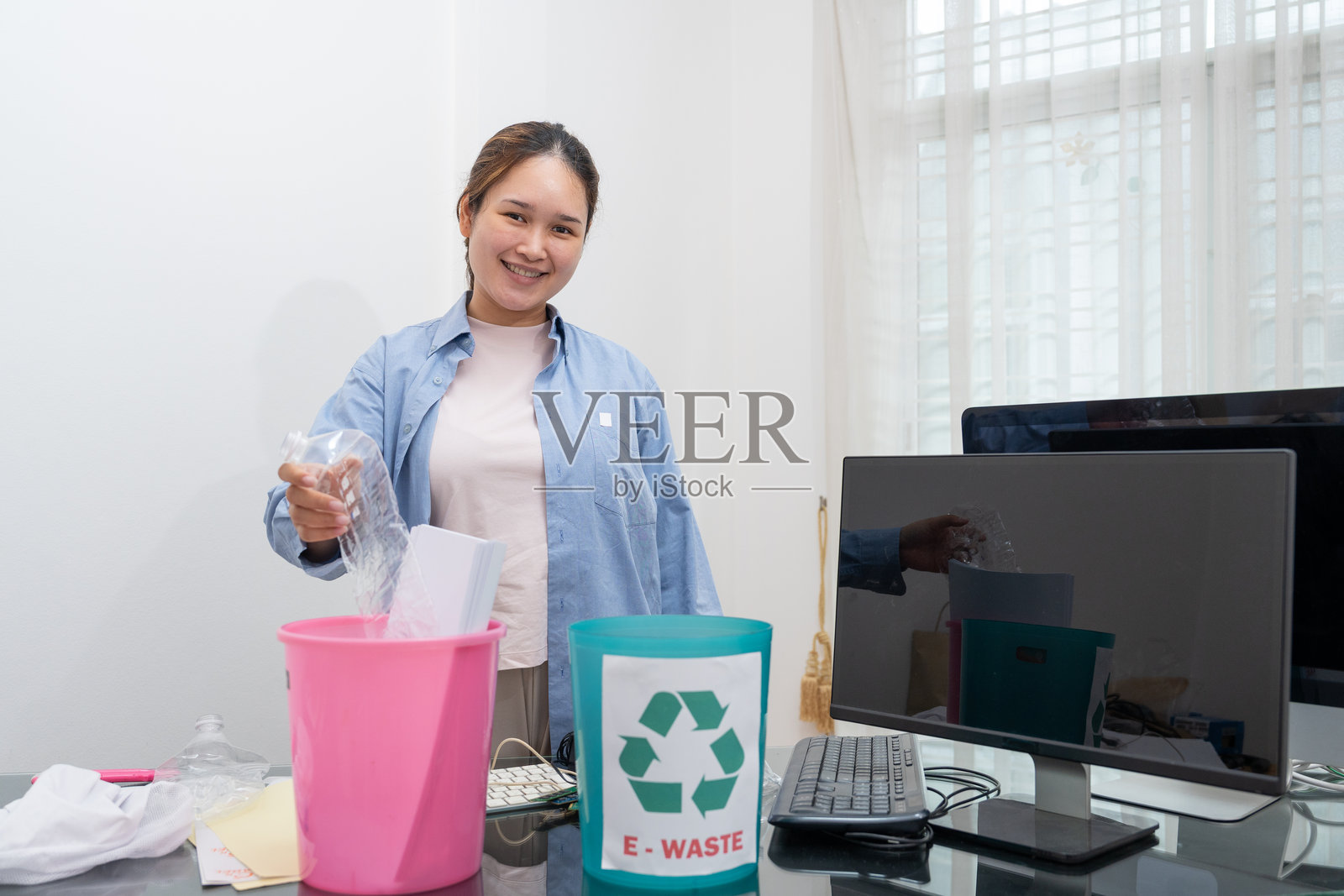 亚洲女性正在将一般垃圾、塑料瓶、纸张和电子废物分开以进行回收。照片摄影图片
