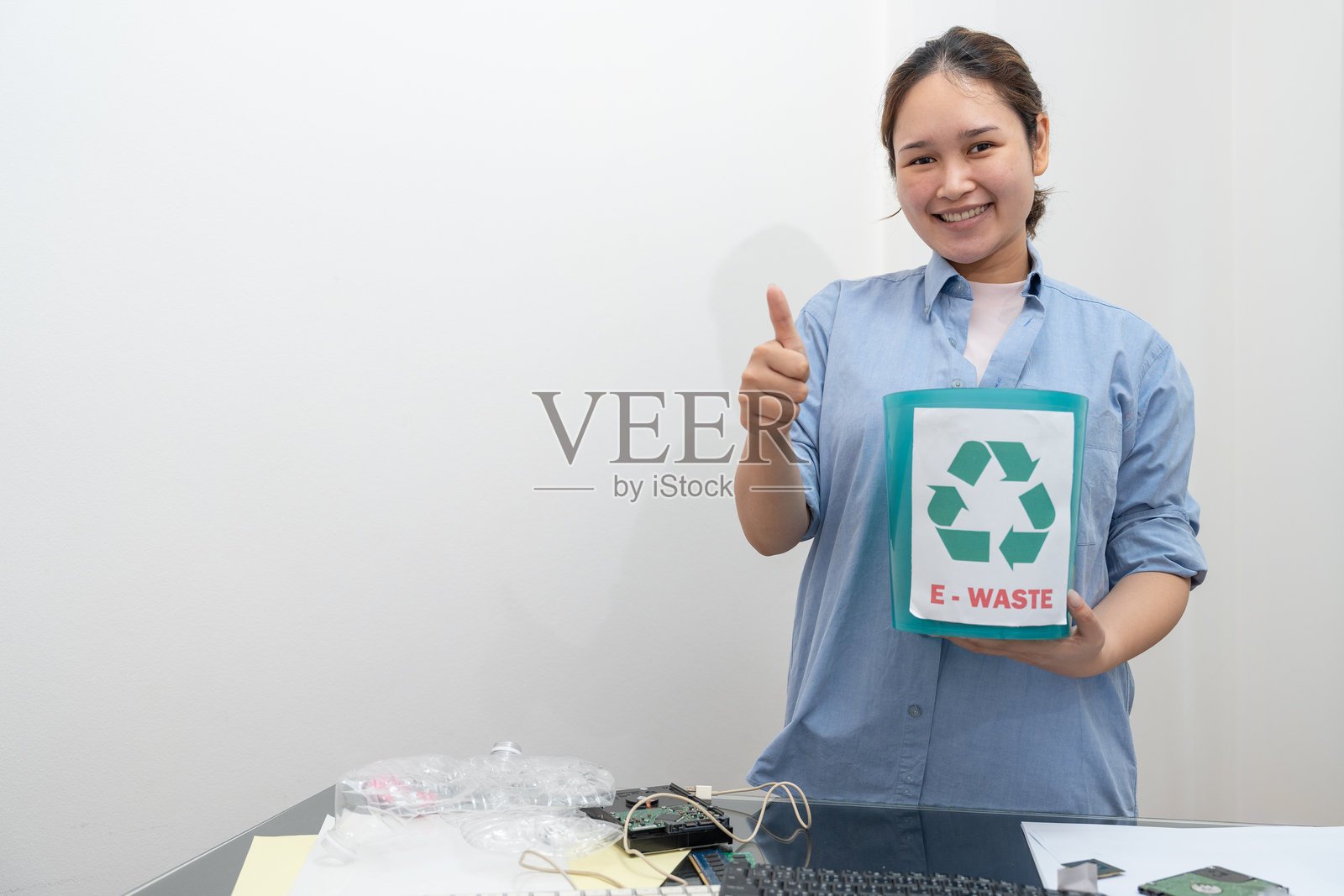 亚洲女性竖起大拇指，手持电子垃圾桶或电子废物进行回收。照片摄影图片