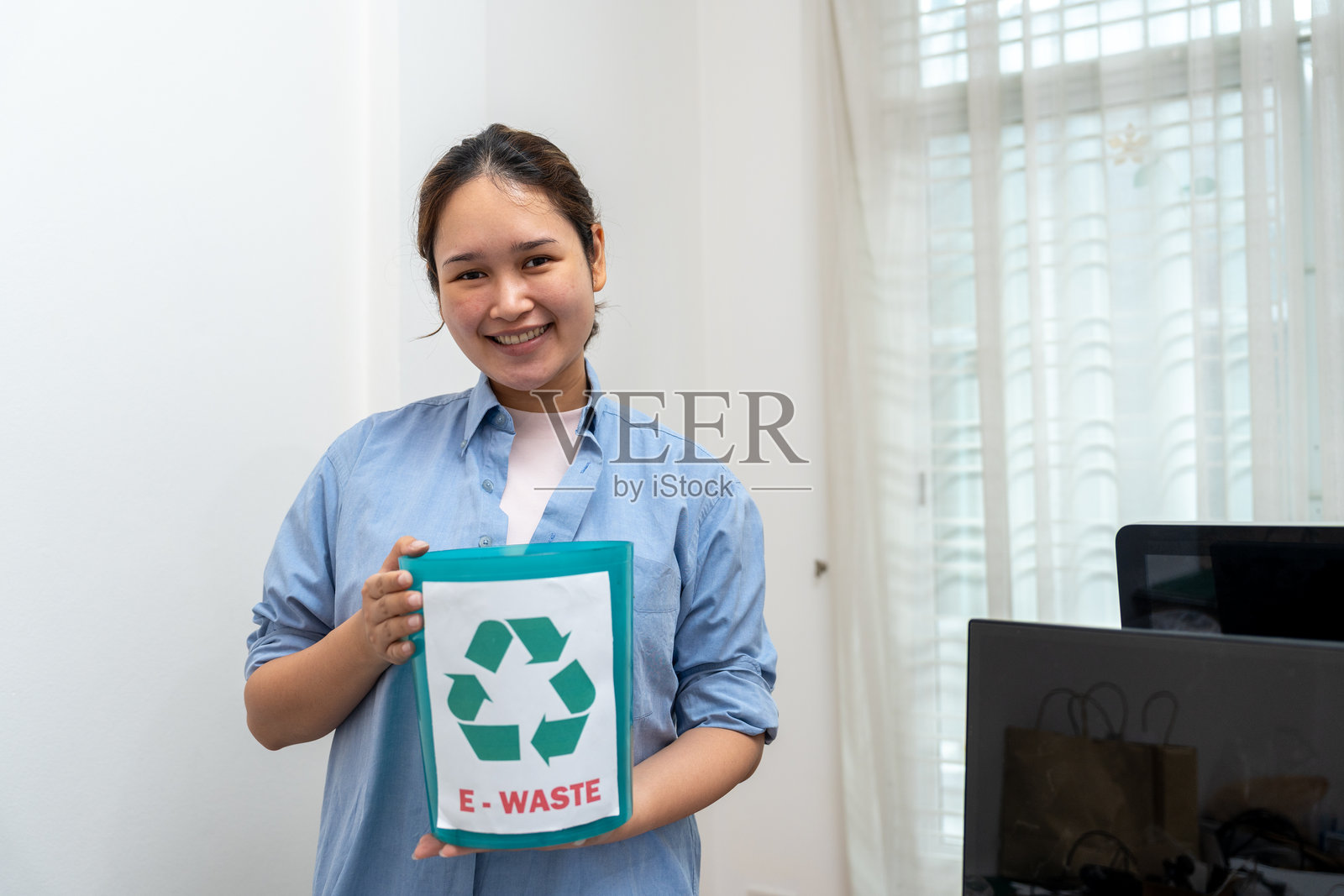 亚洲女性手持电子垃圾桶或电子废物进行回收。照片摄影图片