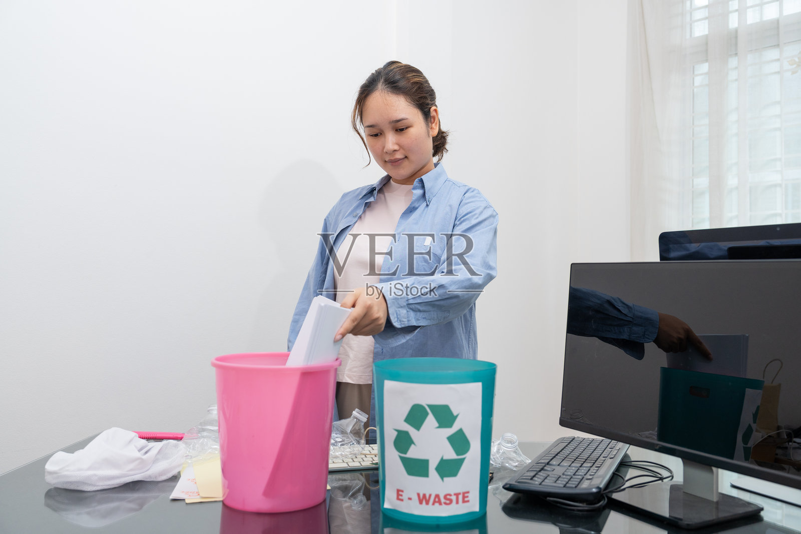 亚洲女性正在将一般垃圾、塑料瓶、纸张和电子废物进行分类以便回收。照片摄影图片