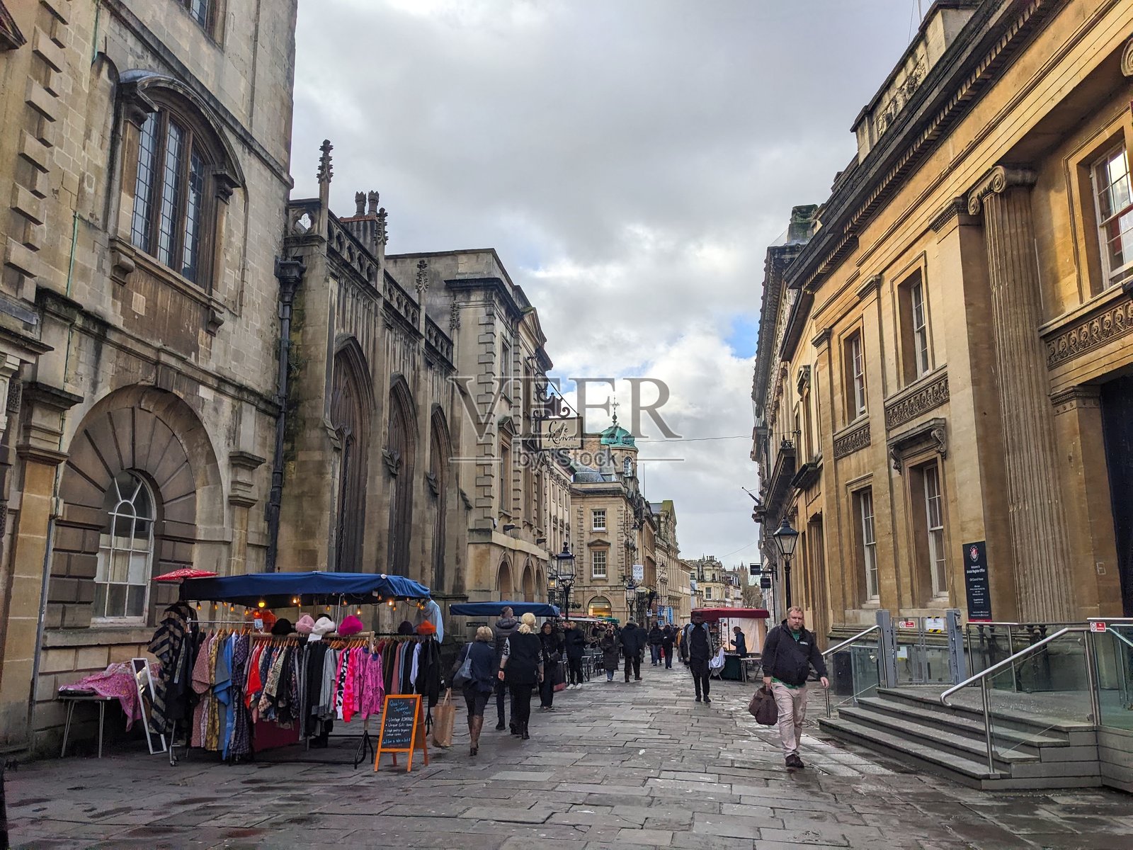 行人漫步在布里斯托尔的宽街,经过古老的石头建筑和市场摊位照片摄影图片