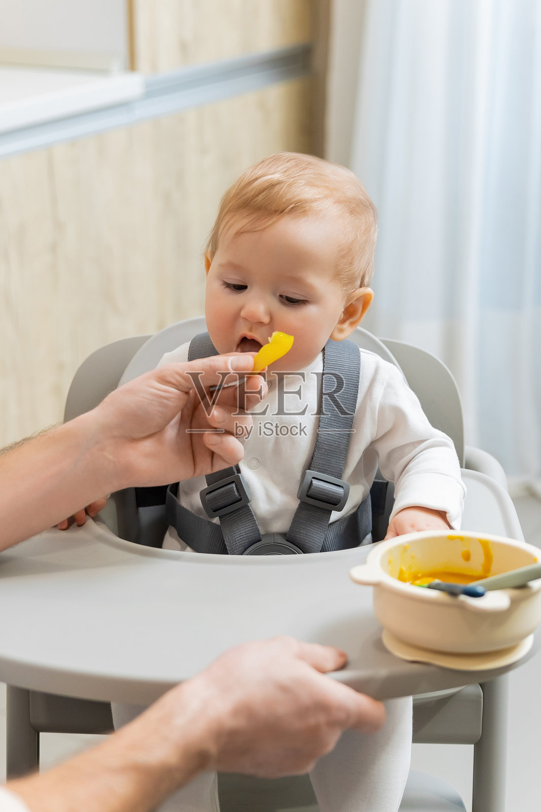 可爱的小男孩坐在椅子上，爸爸正在喂他。照片摄影图片