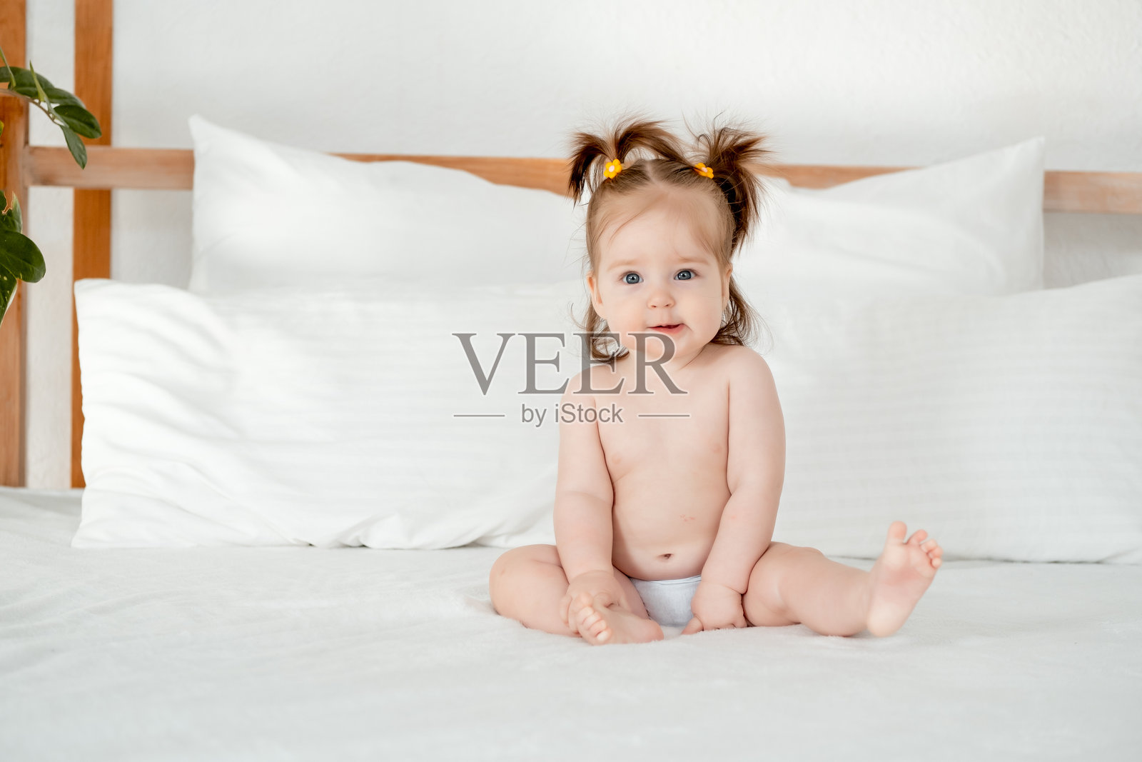 卧室里床上的小女孩穿着尿布，微笑或大笑，家中可爱的宝宝刚刚睡醒，留有文字空间。照片摄影图片