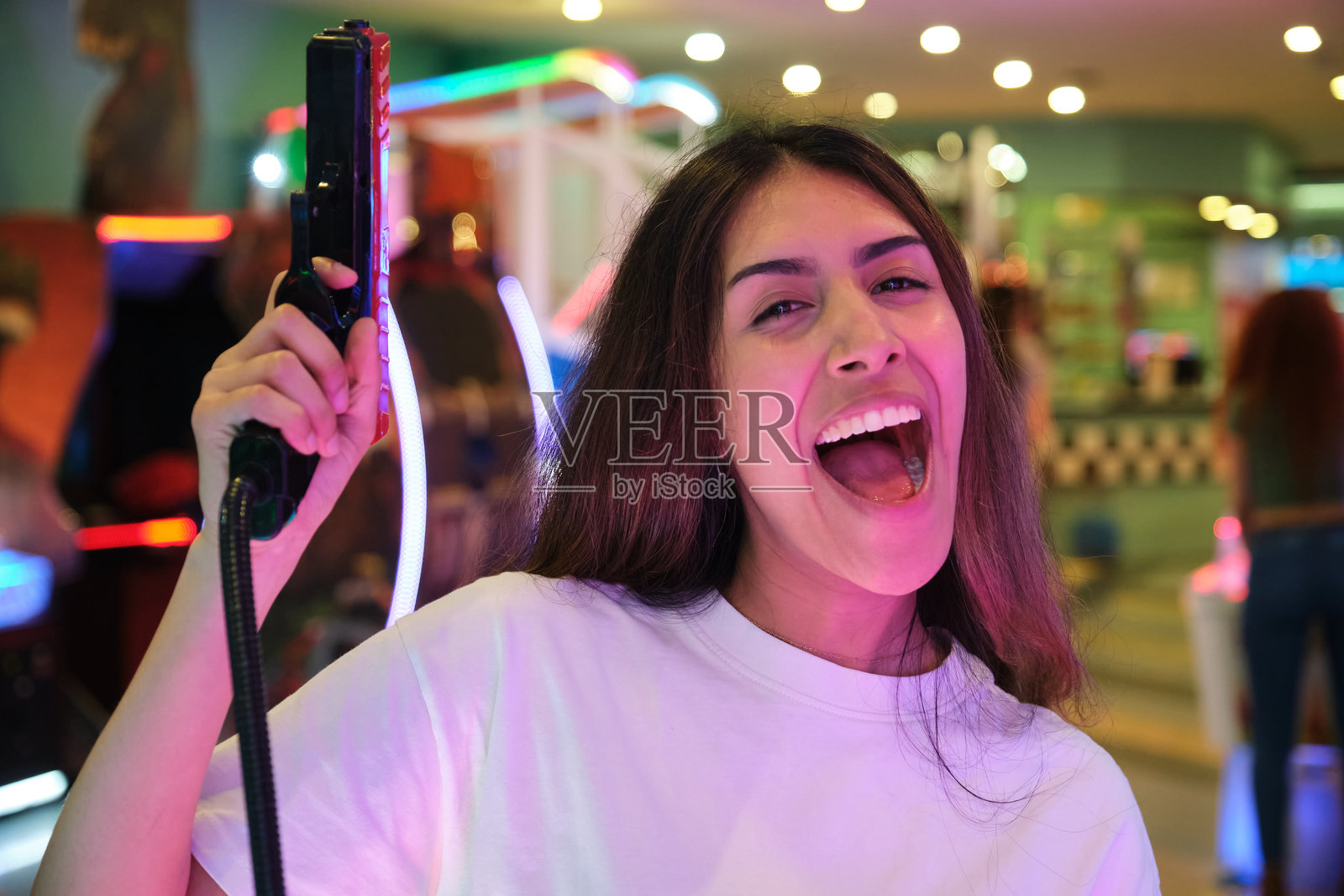 年轻女性在游乐园玩射击游戏，享受乐趣照片摄影图片
