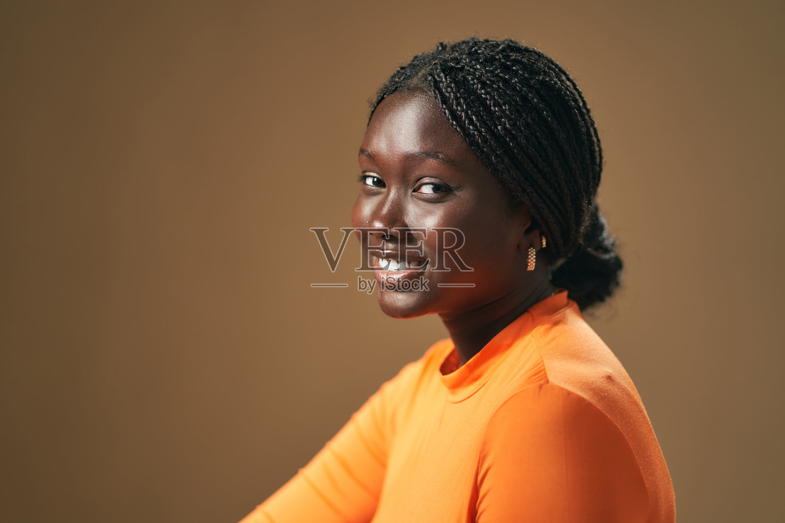 微笑着看向镜头的年轻黑人女性，扎着辫子。照片摄影图片