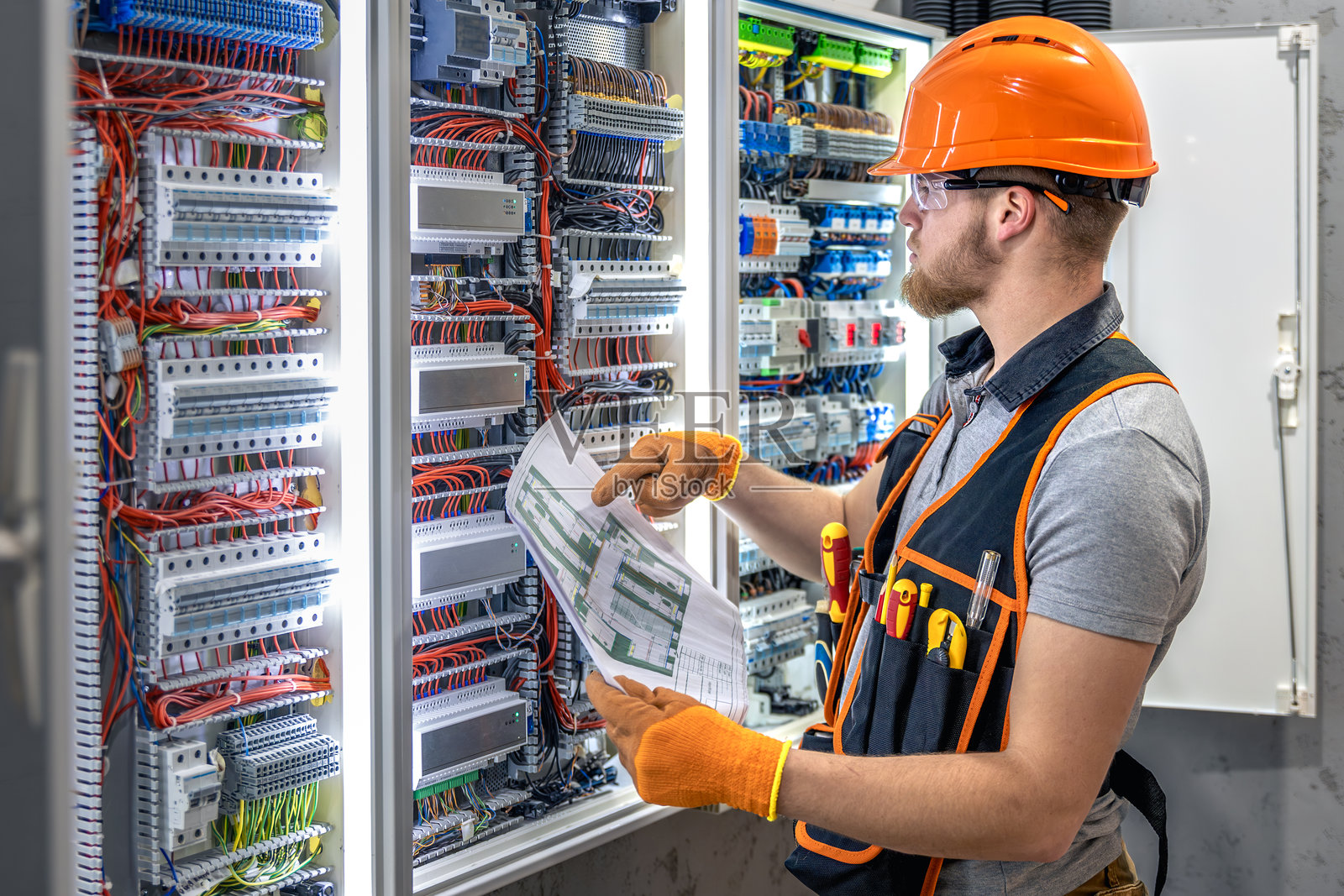 男性电工在电气面板工作。穿着工装的男性电工。照片摄影图片