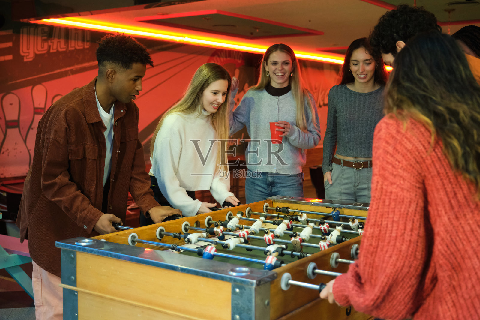 朋友们在保龄球馆一起玩桌上足球，享受快乐时光照片摄影图片