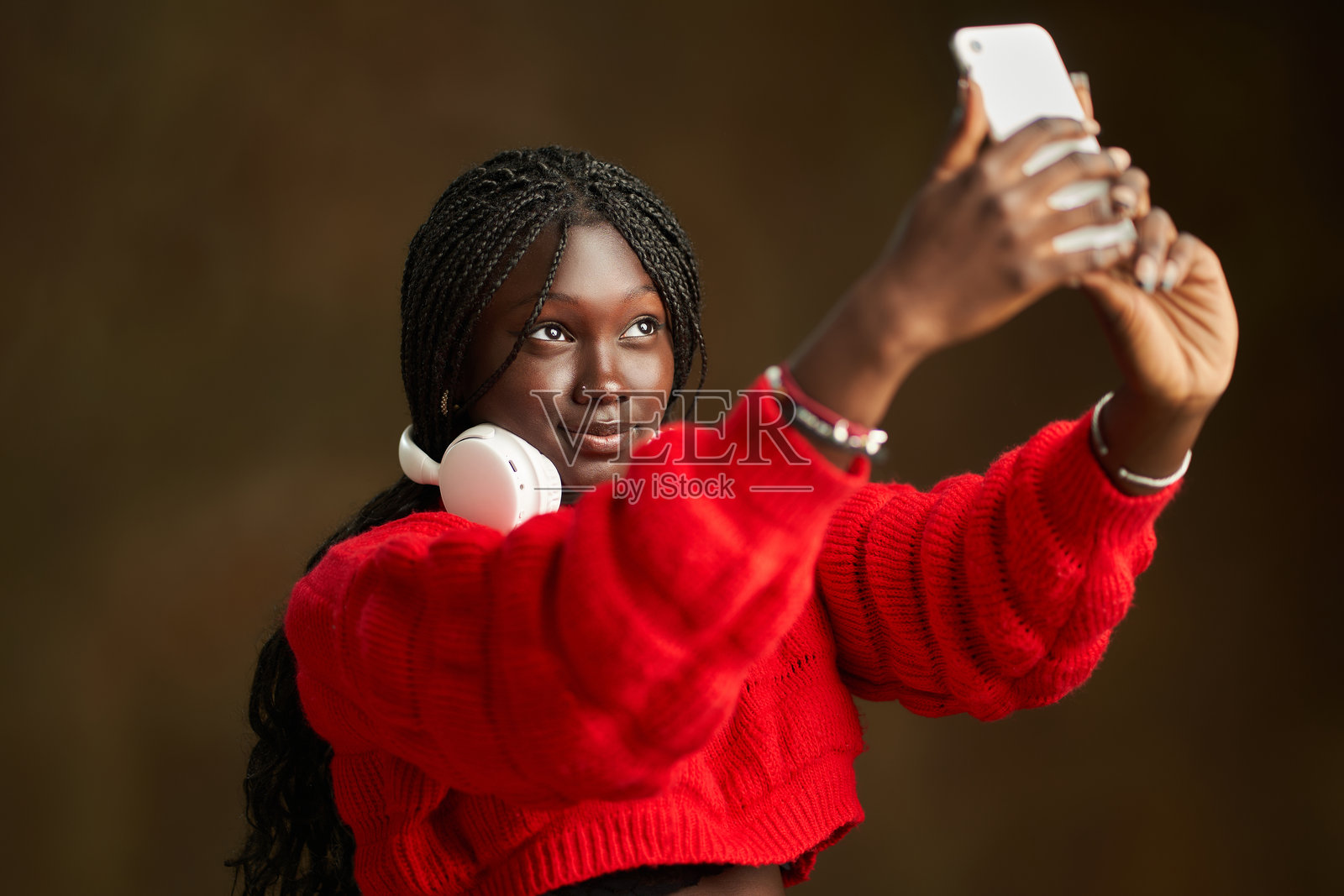 年轻女性穿着红色毛衣，戴着耳机自拍照片摄影图片
