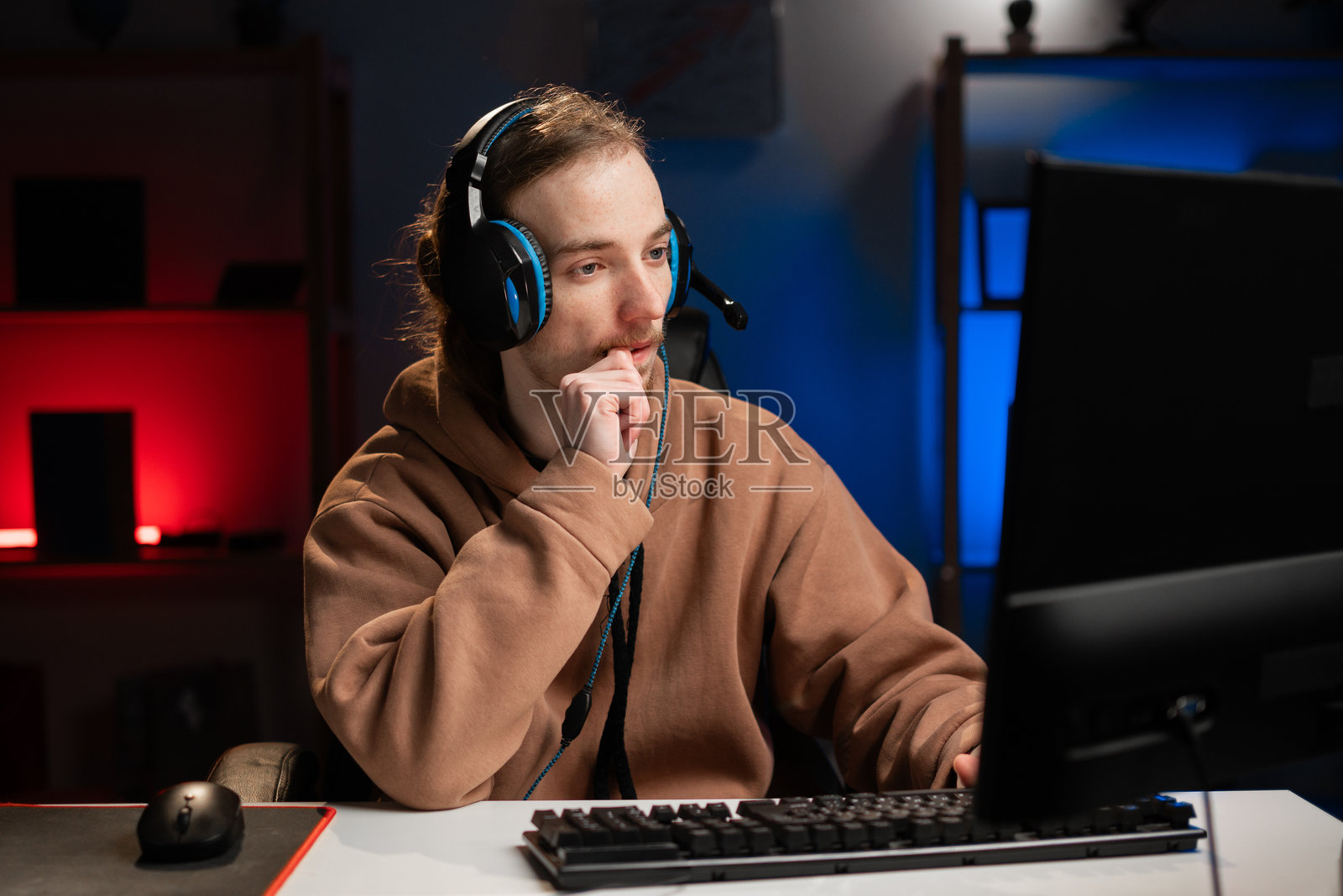 年轻的白人嬉皮士职业玩家在家夜间玩网络电子竞技游戏时紧张地咬指甲照片摄影图片