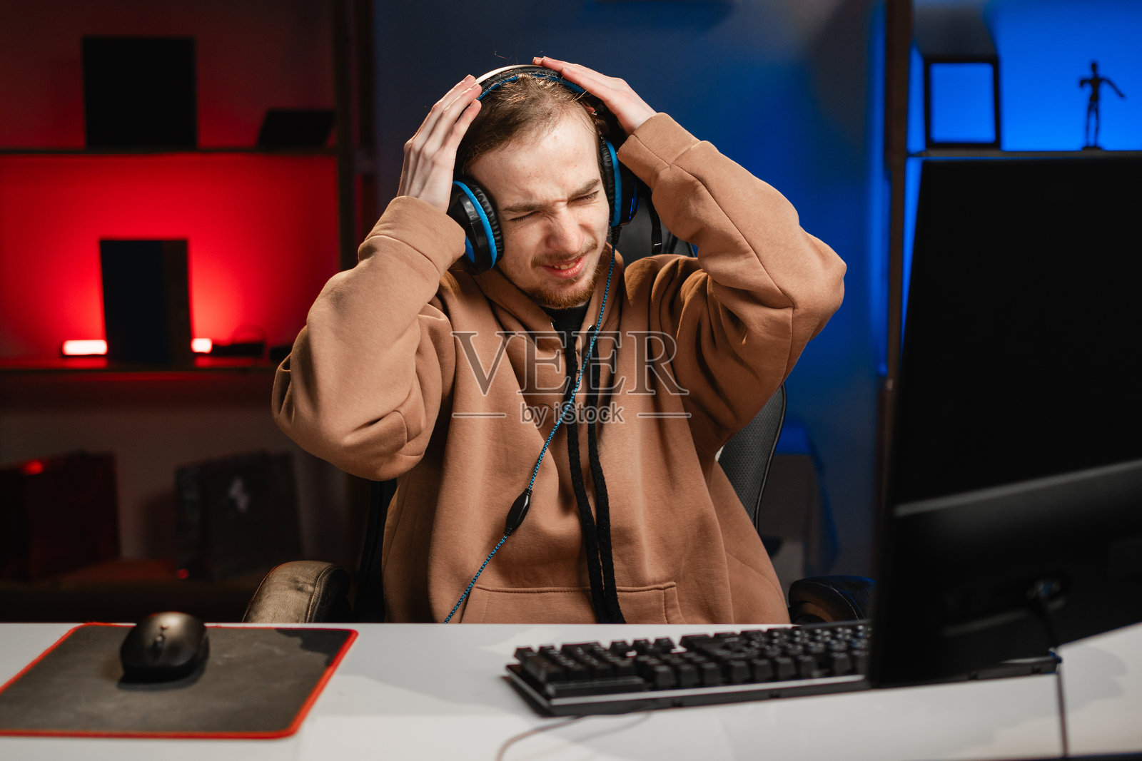 失望且愤怒的游戏主播在家中夜间直播，感到压力，思考问题。照片摄影图片