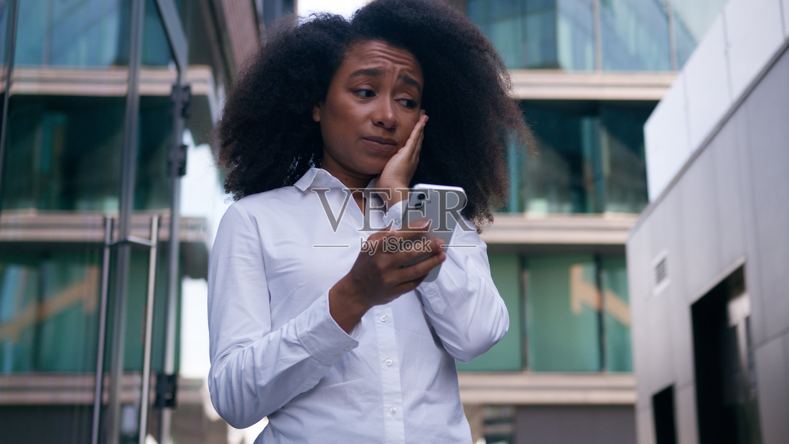 震惊和不满的非裔美国女性商人，户外持手机，面临问题和坏消息，失败的错误信息，城市中的员工和企业家。照片摄影图片