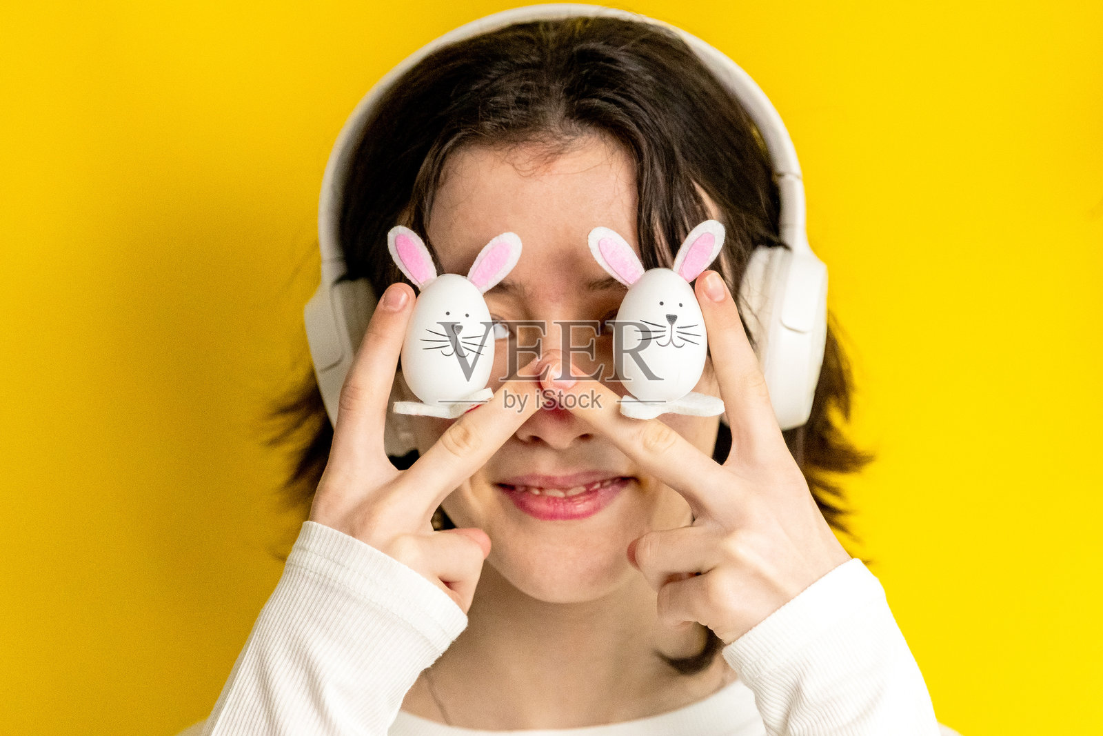 一个少女在眼前举着两个复活节兔子。照片摄影图片