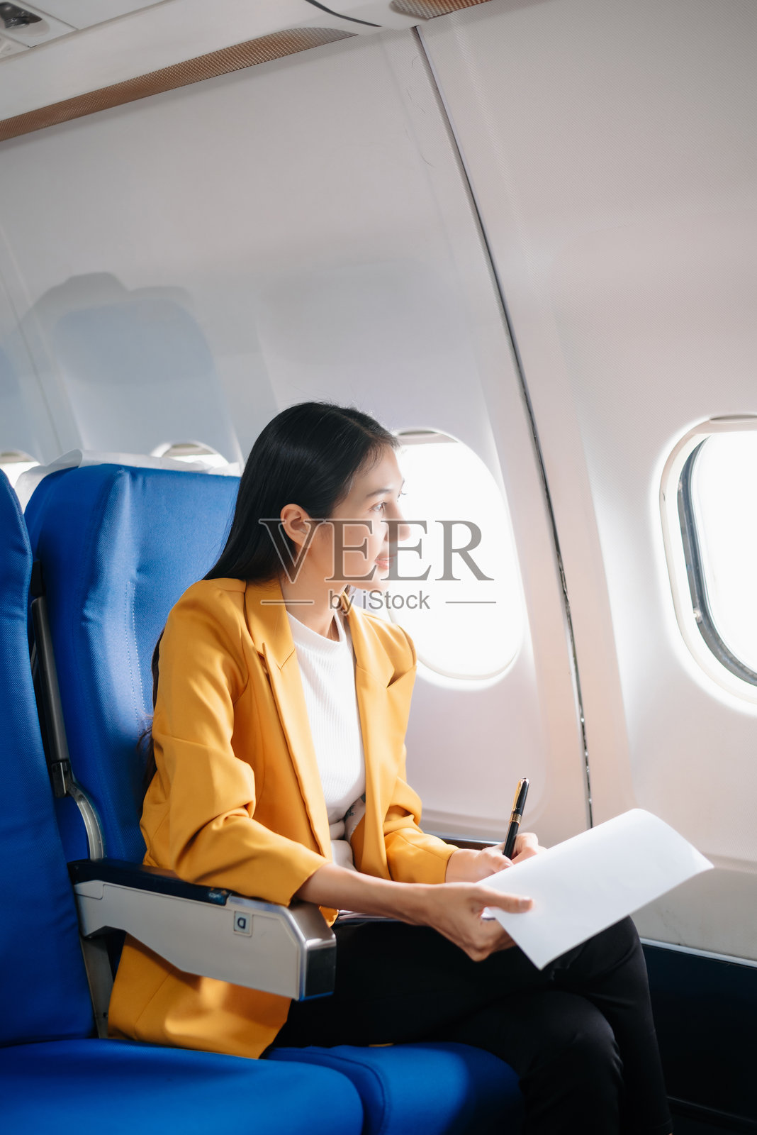 亚洲女性坐在飞机座位上，望着窗外，享受旅行度假的概念。照片摄影图片
