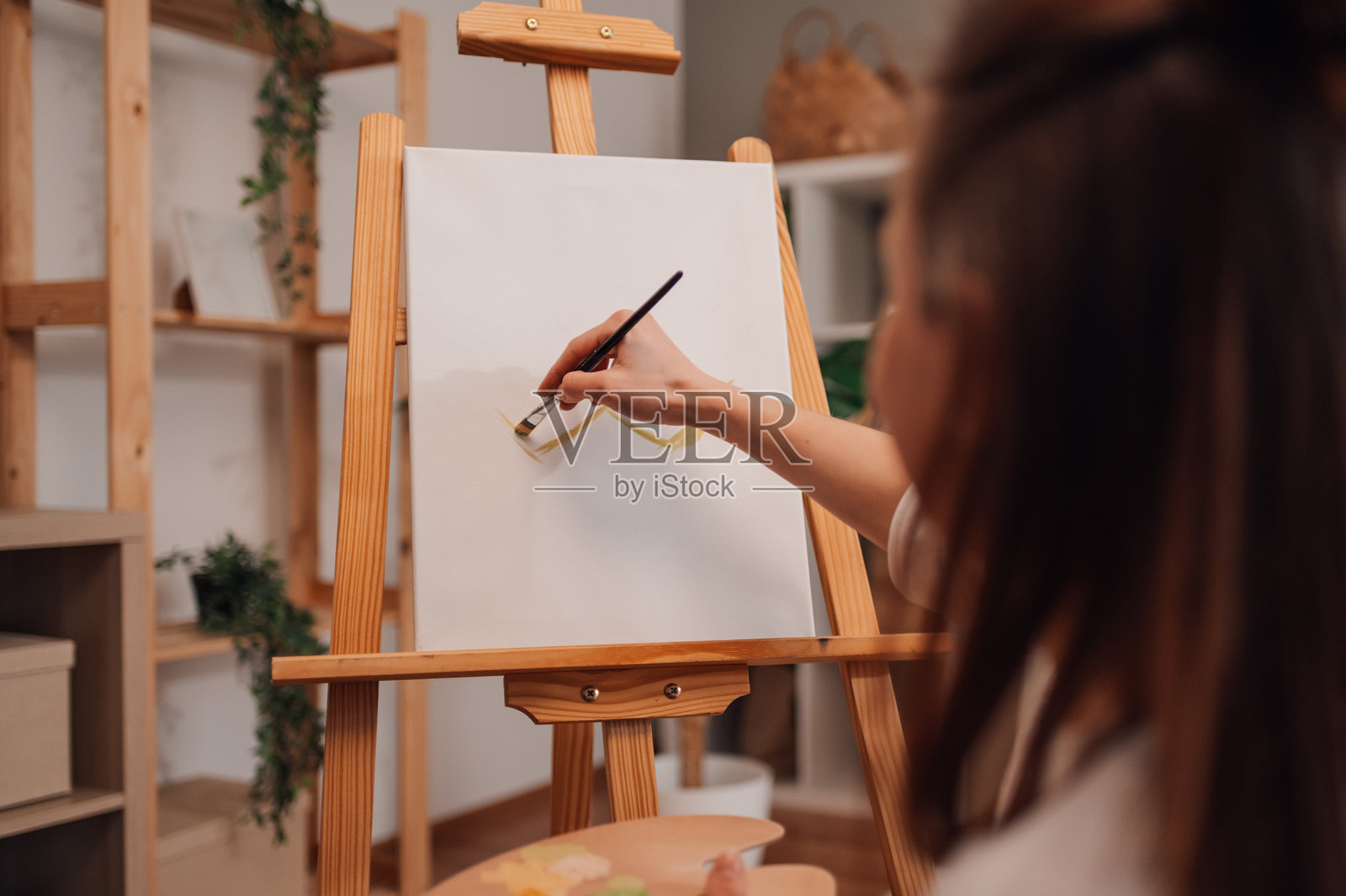 女性艺术家在艺术工作室用画笔在画布上作画照片摄影图片