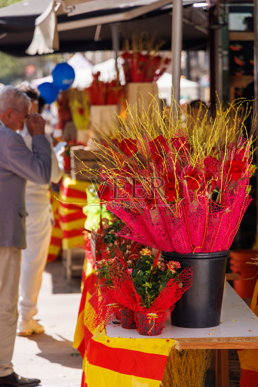 在巴塞罗那的拉姆布拉大道,庆祝圣乔治节的人群在摊位上购买玫瑰和书籍。照片摄影图片
